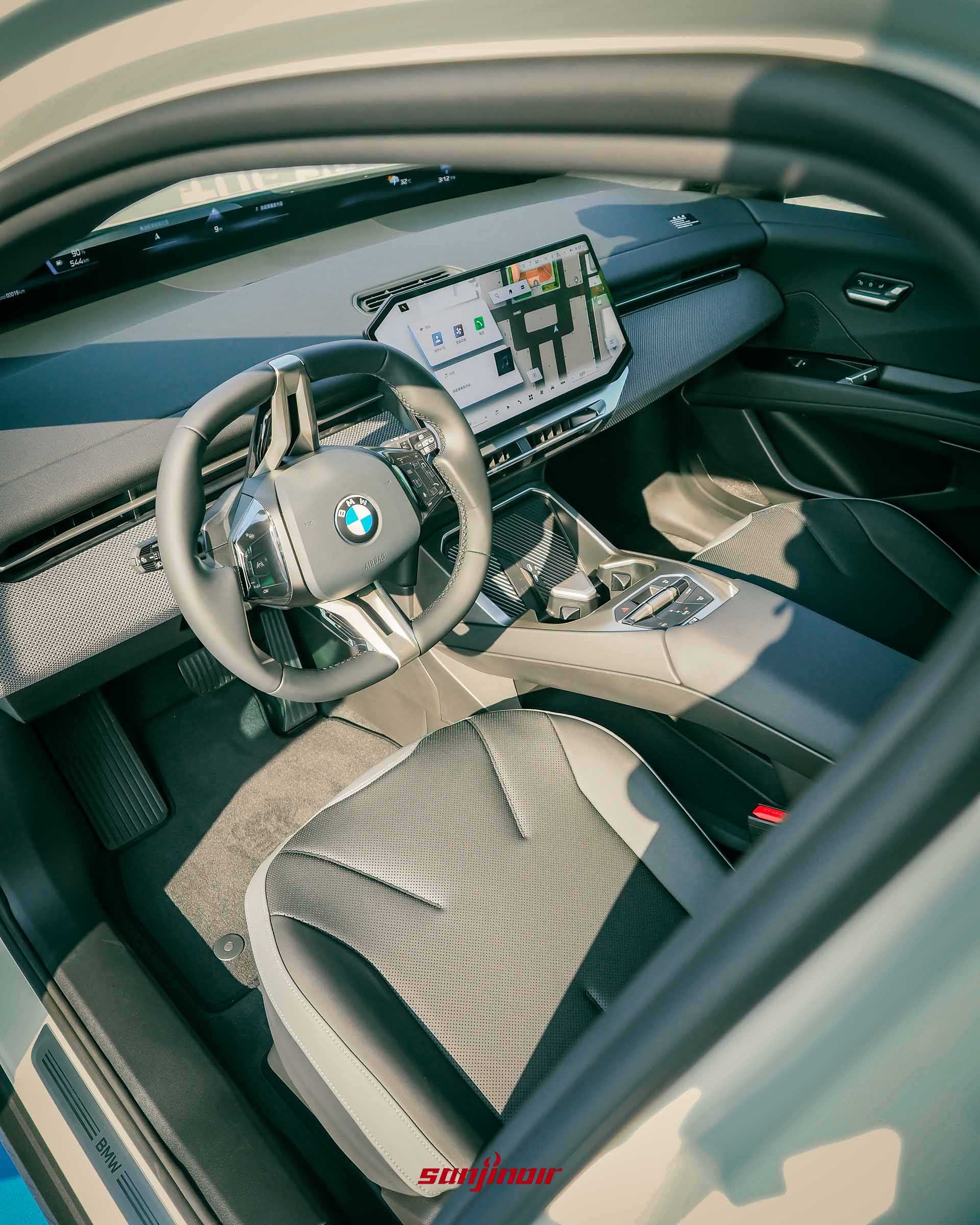 BMW iX3前座內裝全景，包含大型懸浮式中控螢幕、全新方向盤、中央扶手與駕駛座設計。