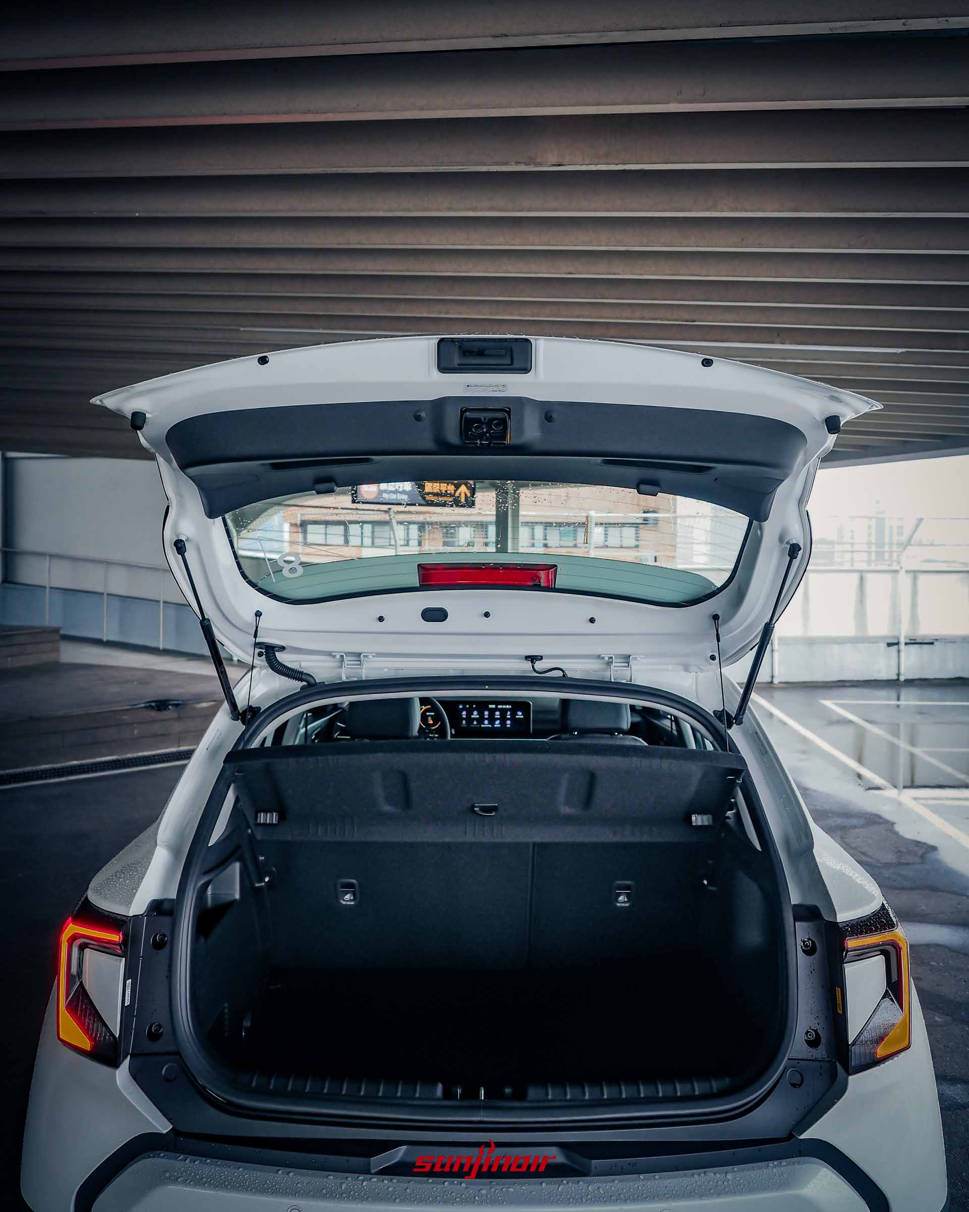 白色2026 Kia Stonic掀開後車廂尾門的正後方視角,展示平整的行李廂空間與上方的遮物板。