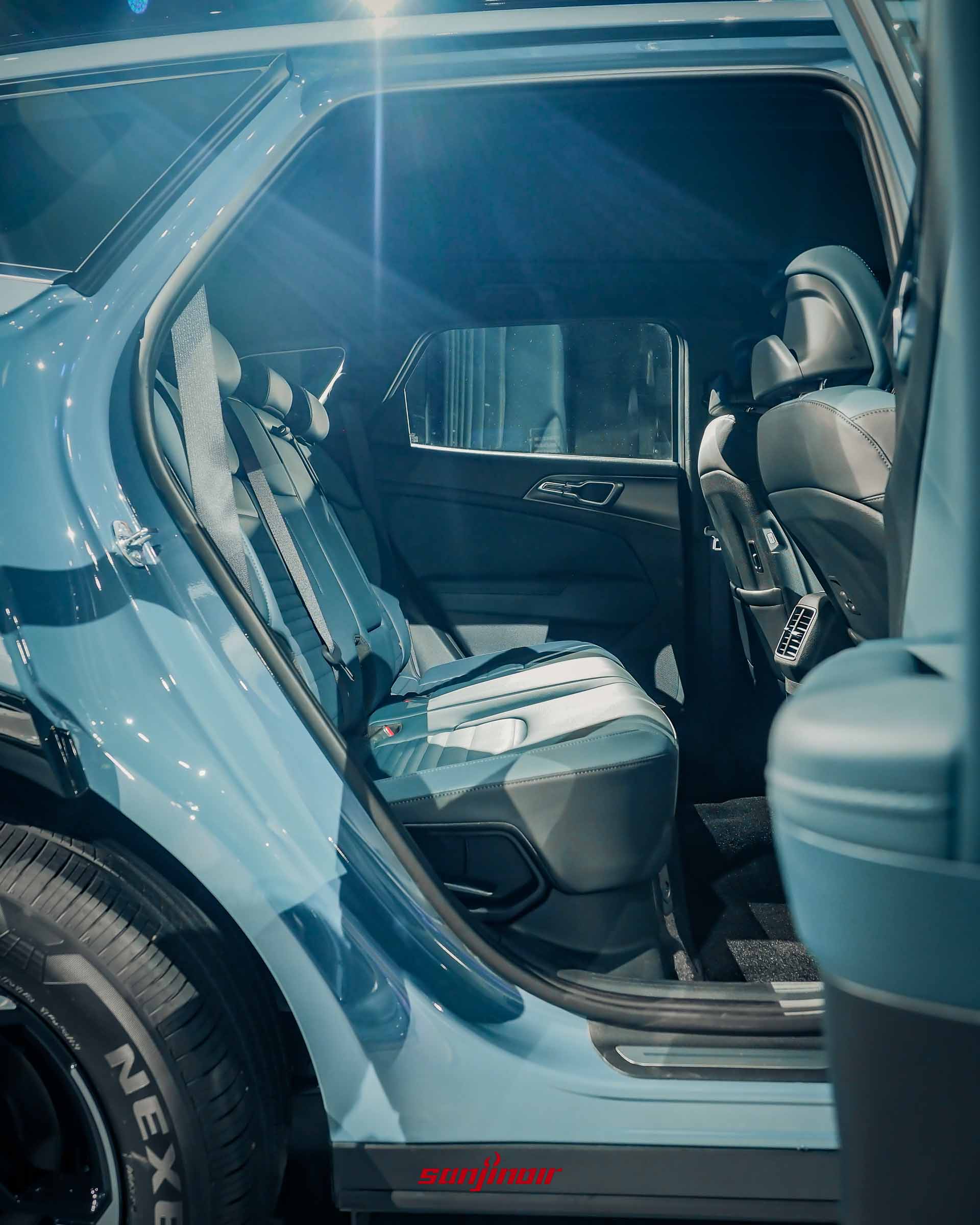 從車外看向Kia Sportage晨霧藍車型的後座，展示雙色皮質座椅、後座冷氣出風口、前座椅背上的USB充電孔，車門飾板為晨霧藍色。