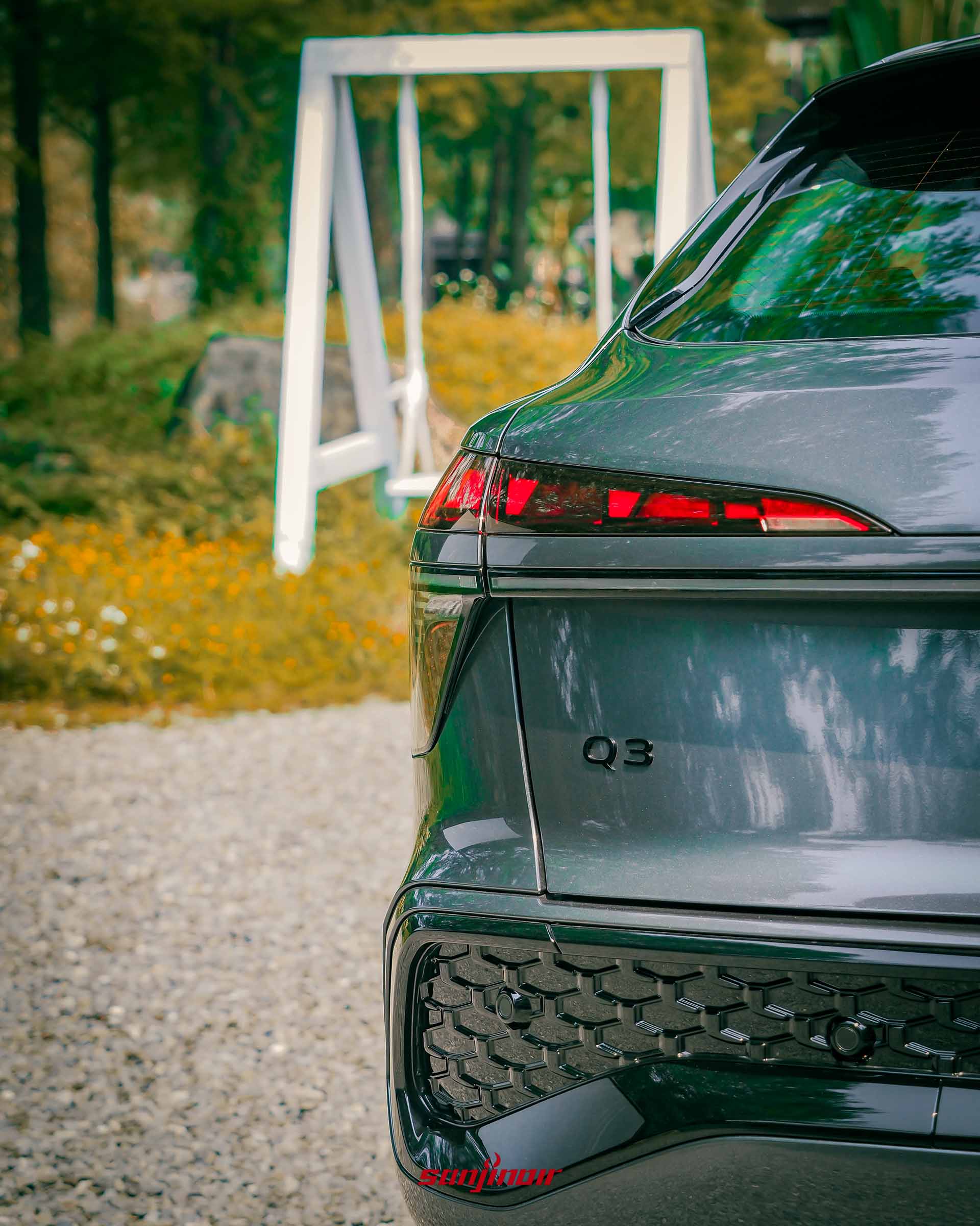 Audi Q3左後尾燈特寫，展示黑化的Q3字樣與保桿網狀細節。