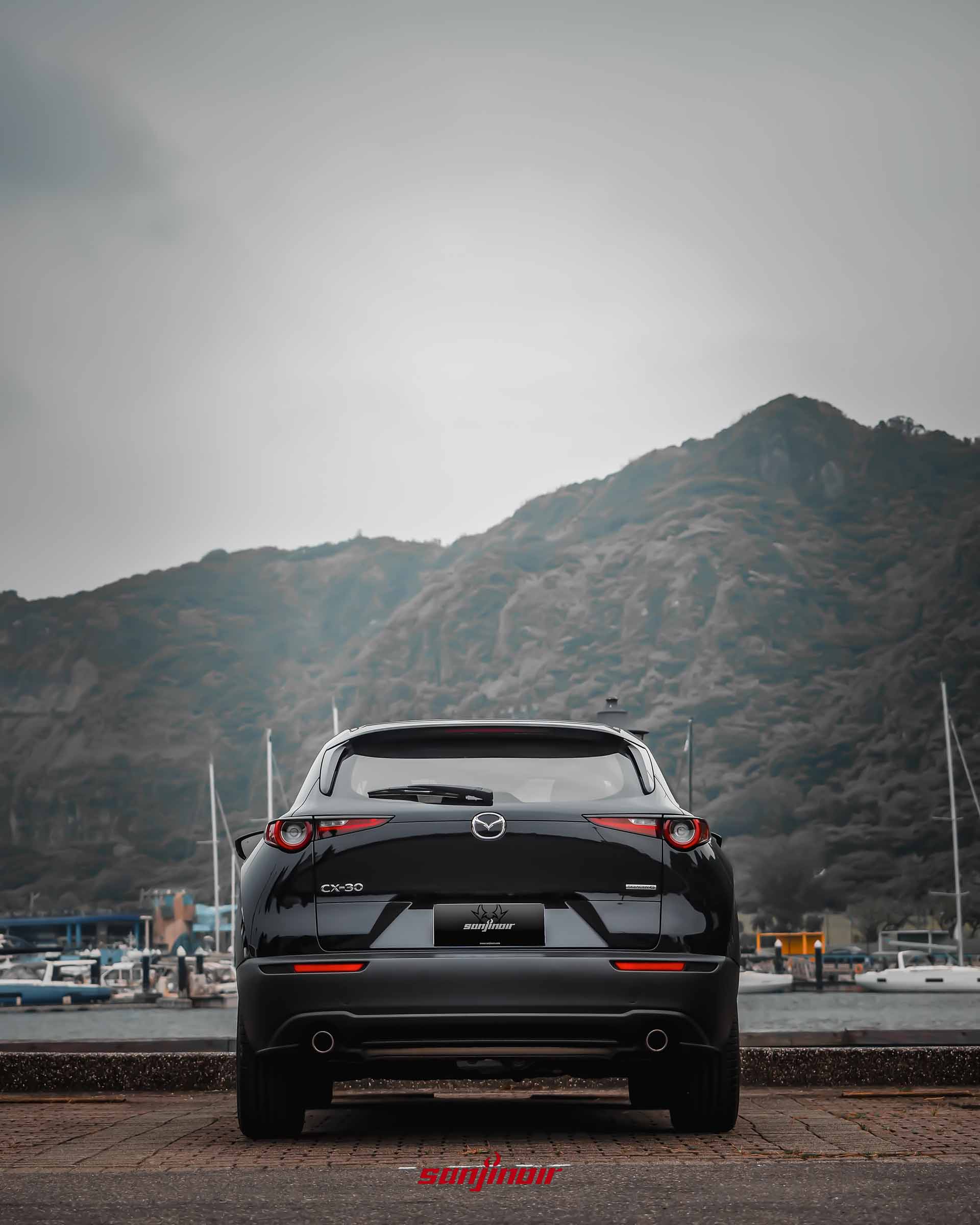 黑色MAZDA CX-30 20S Homura車尾正視圖,停放於碼頭旁,展示燻黑尾燈與雙邊單出尾管。