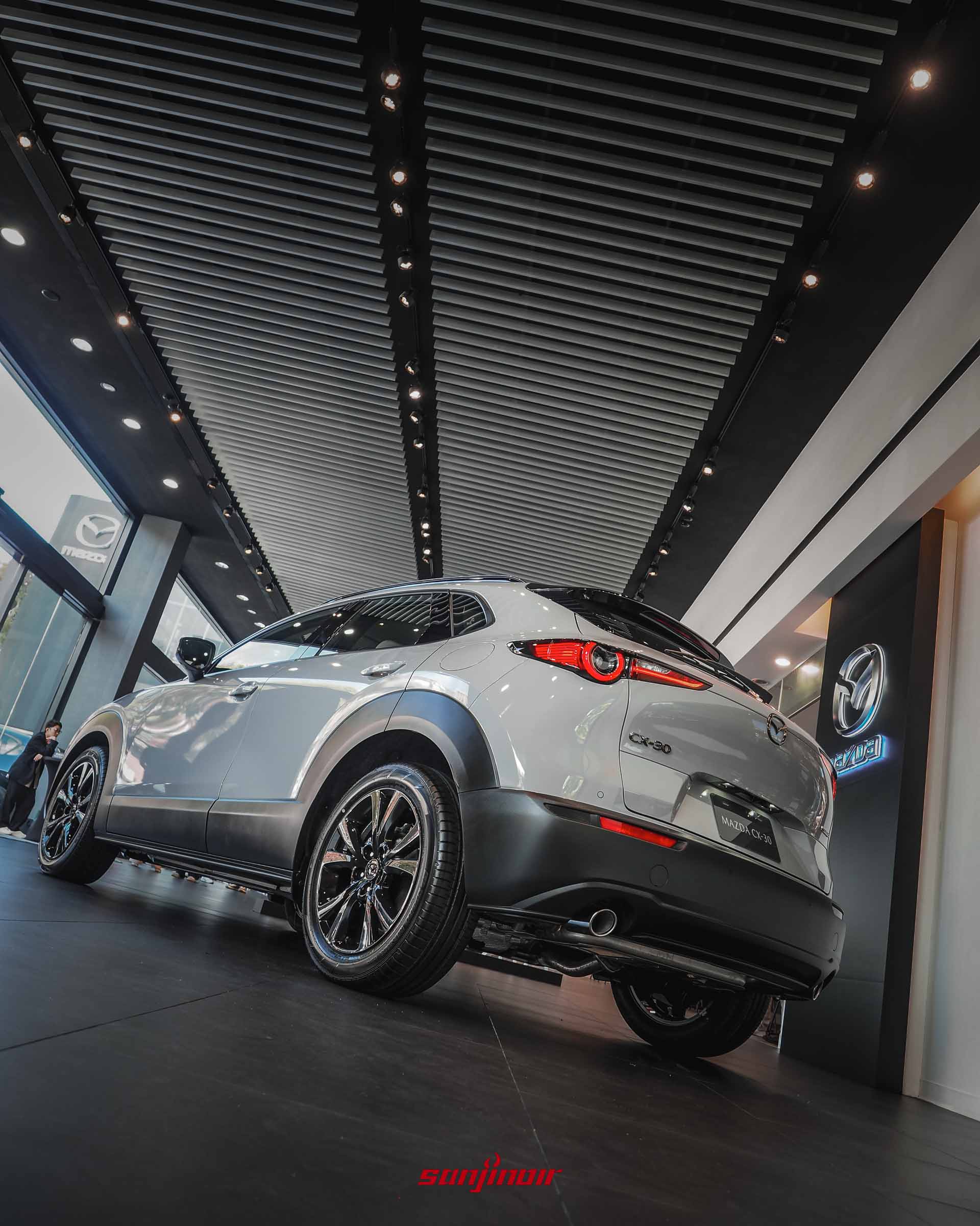 低角度拍攝的MAZDA CX-30 Air Edition右後方45度角全車照,展示車尾線條、尾燈、雙出排氣尾管及18吋黑化鋁合金輪圈。