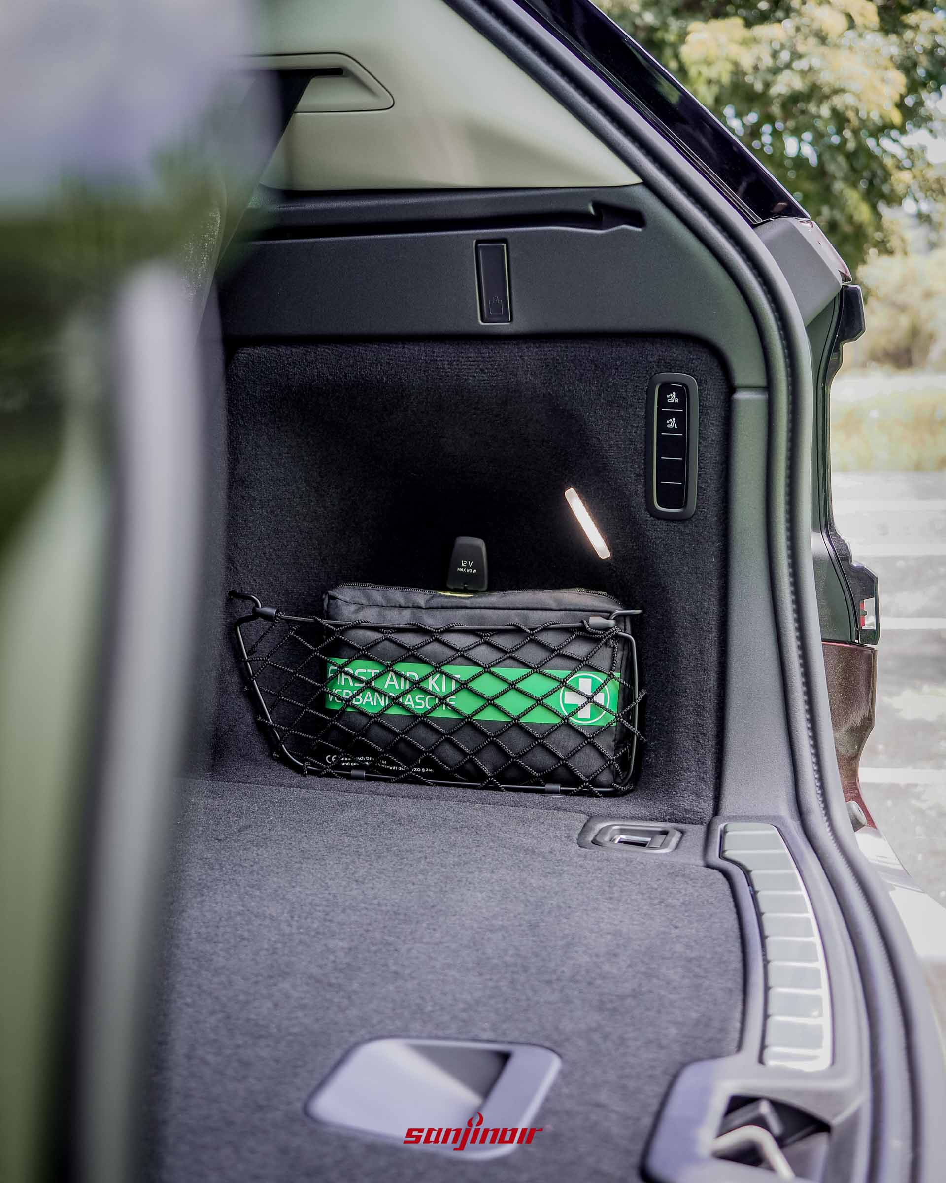 Volvo EX90後車廂左側的特寫,展示急救包收納網、LED照明燈與電動按鍵控制面板。