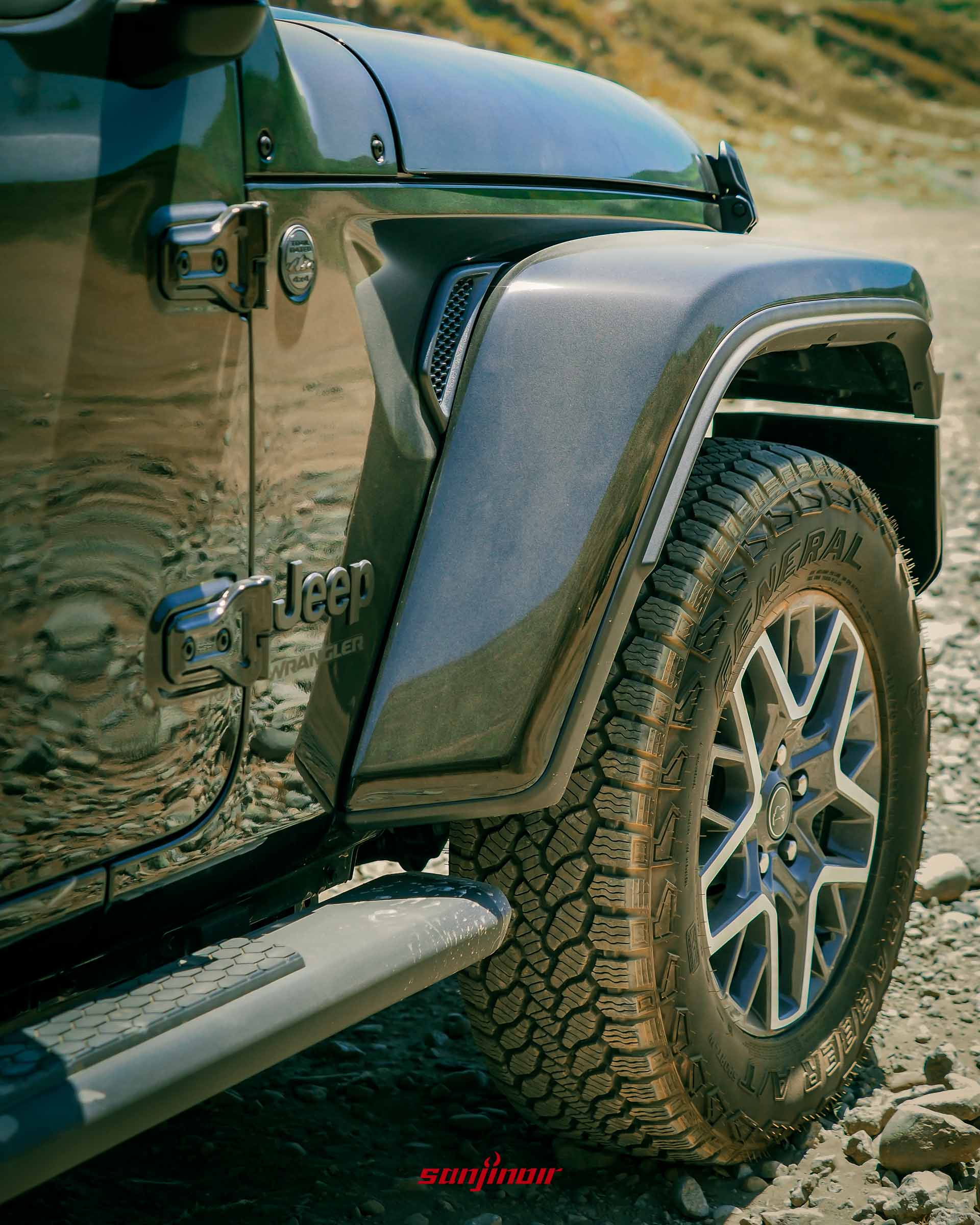 Jeep Wrangler Sahara 的車側特寫,包含前葉子板上的 Jeep 及 Wrangler 字樣銘牌、散熱孔,以及部分前輪圈與全地形胎。