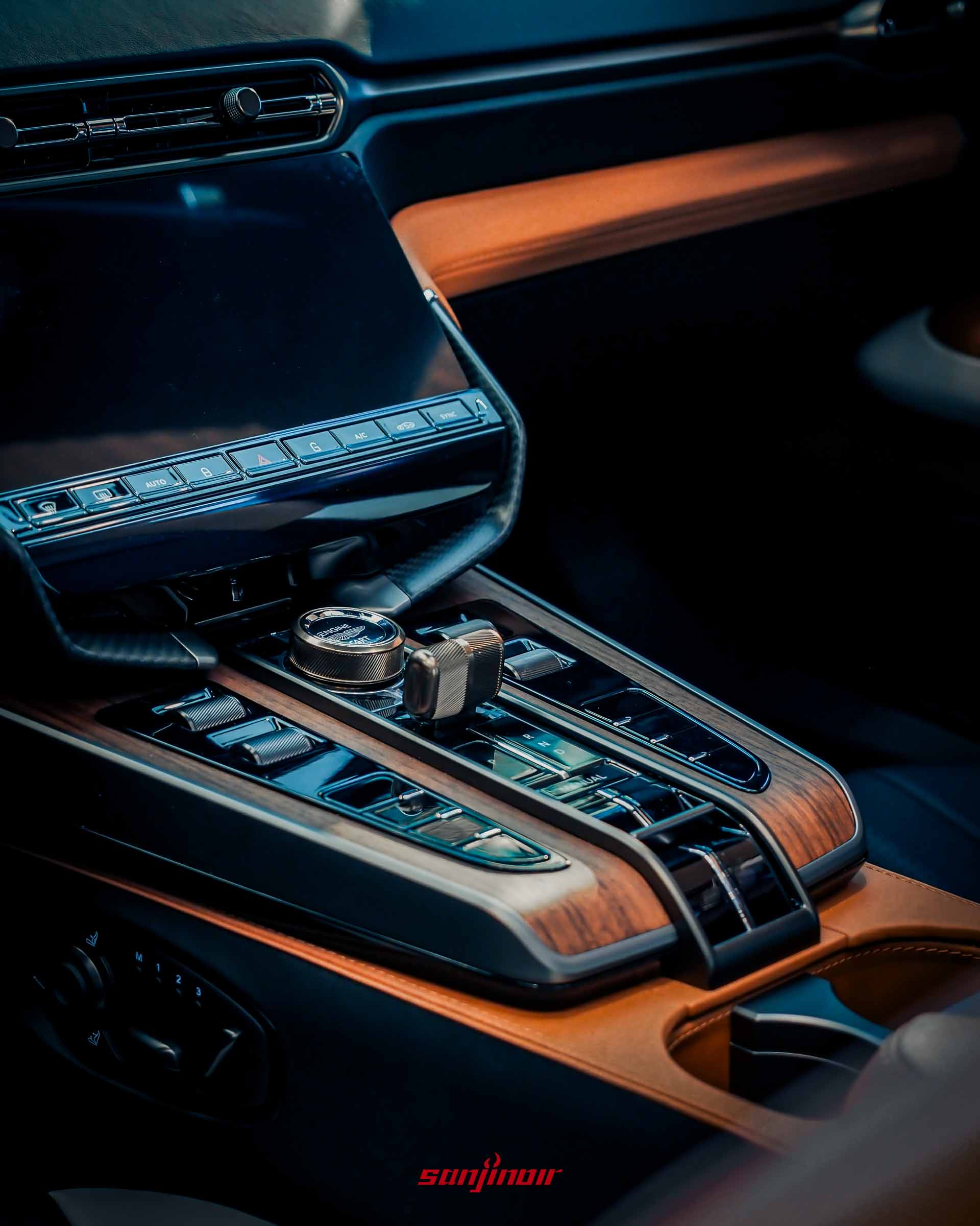 Vanquish Volante 60th Anniversary Edition 中控台細節，展示古銅金屬旋鈕、多功能排檔座、深色胡桃木飾板和觸控螢幕下方區域。