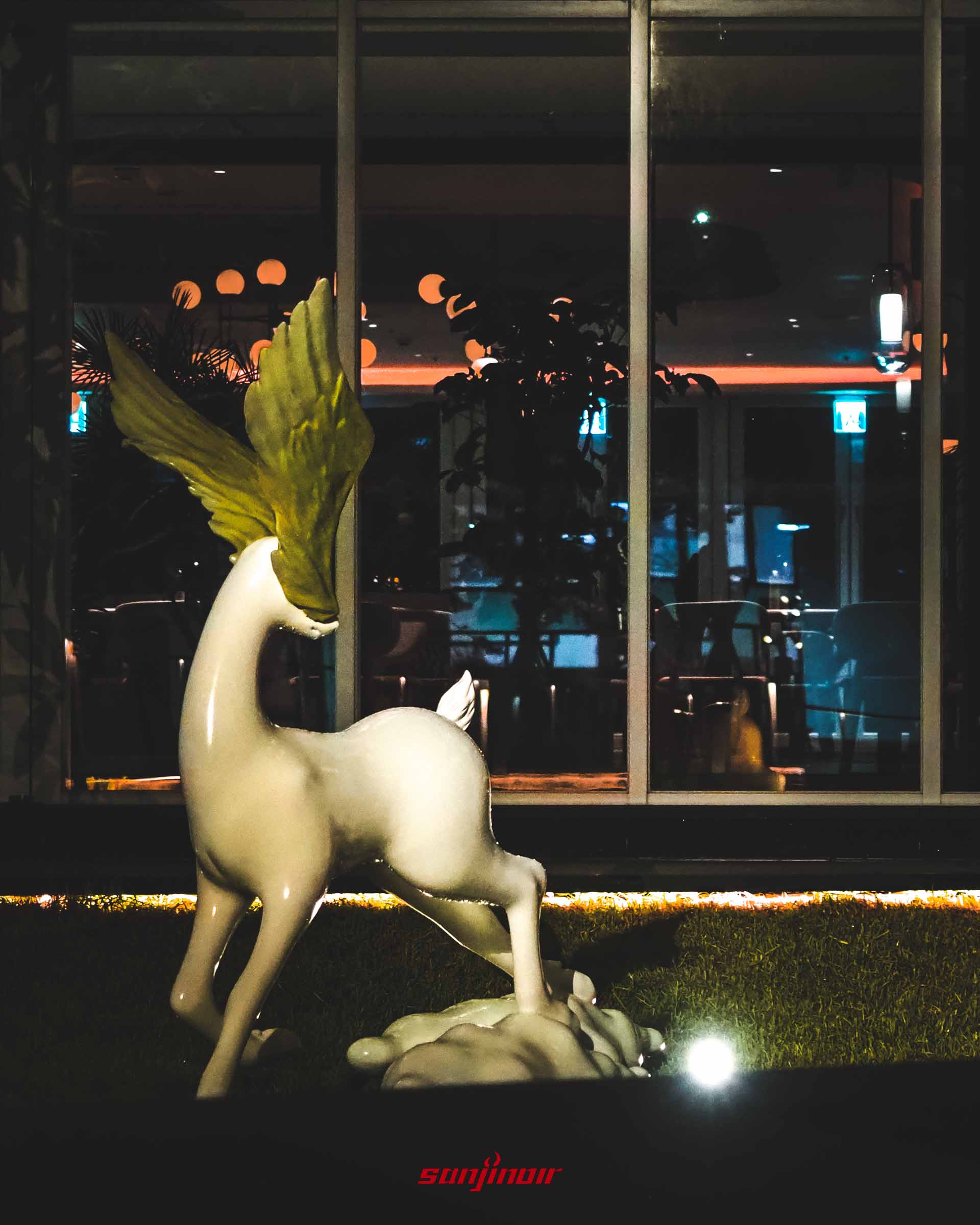 戶外草地上的白色動物雕塑,頭上長著綠色葉片般的裝飾。