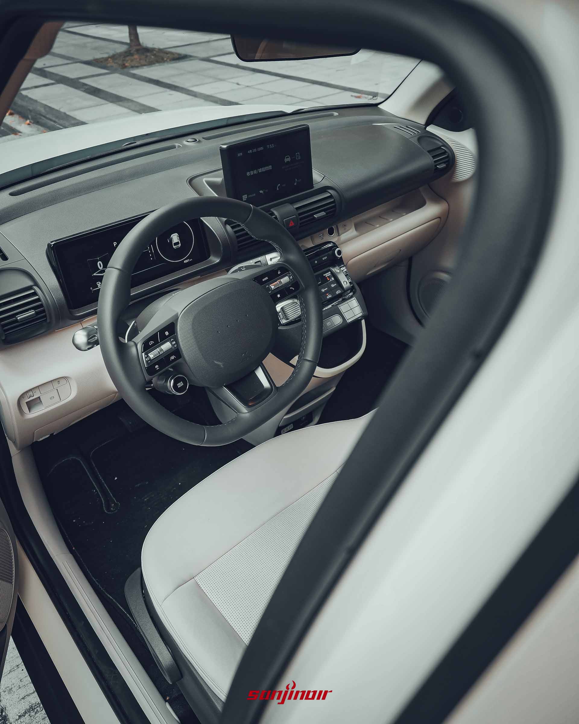 Hyundai Inster 內裝前座全景，顯示雙螢幕與實體按鍵。