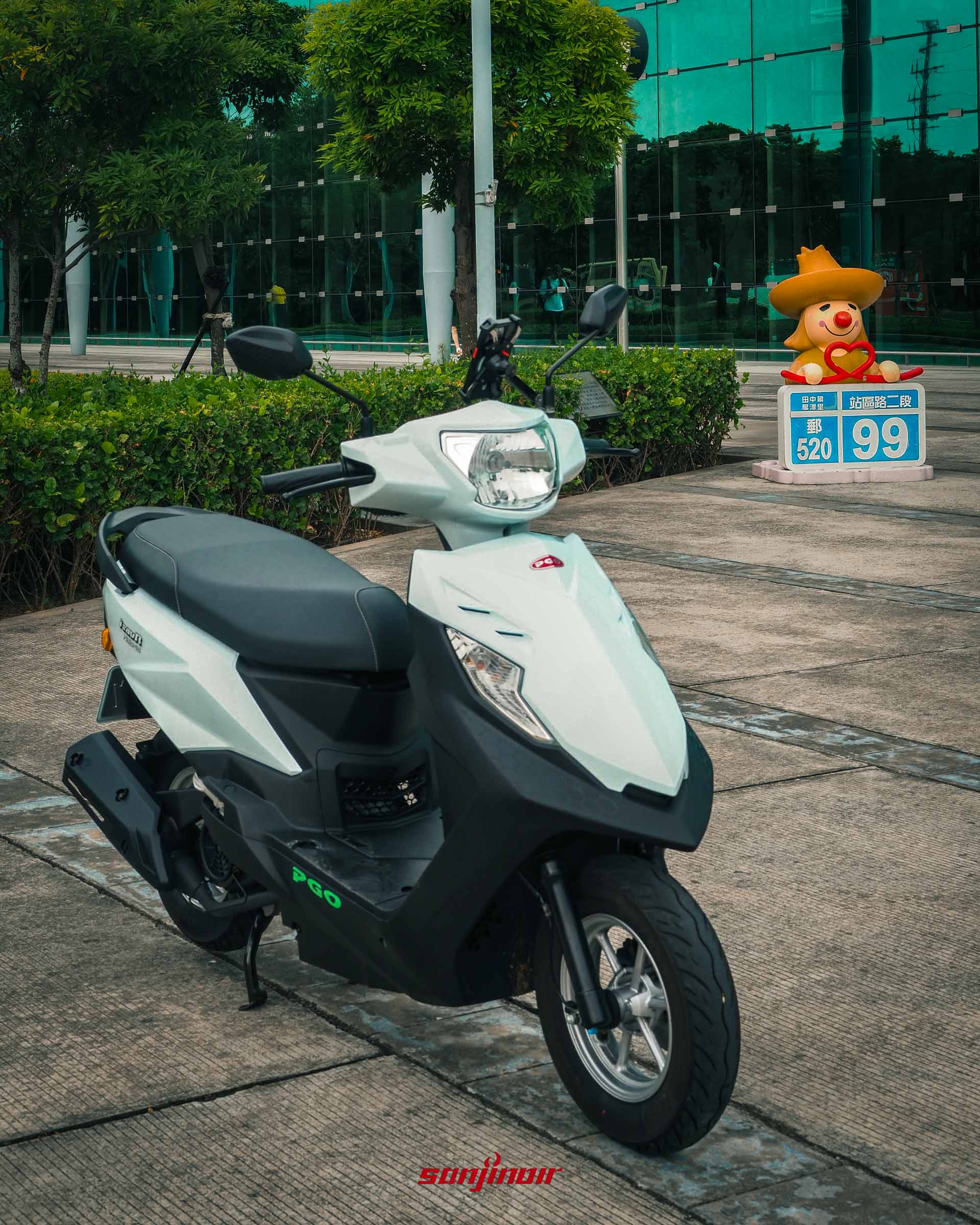 白色PGO isavR威力125停放在彰化高鐵站前,右側有著結合郵遞區號520與門牌99的趣味造景。
