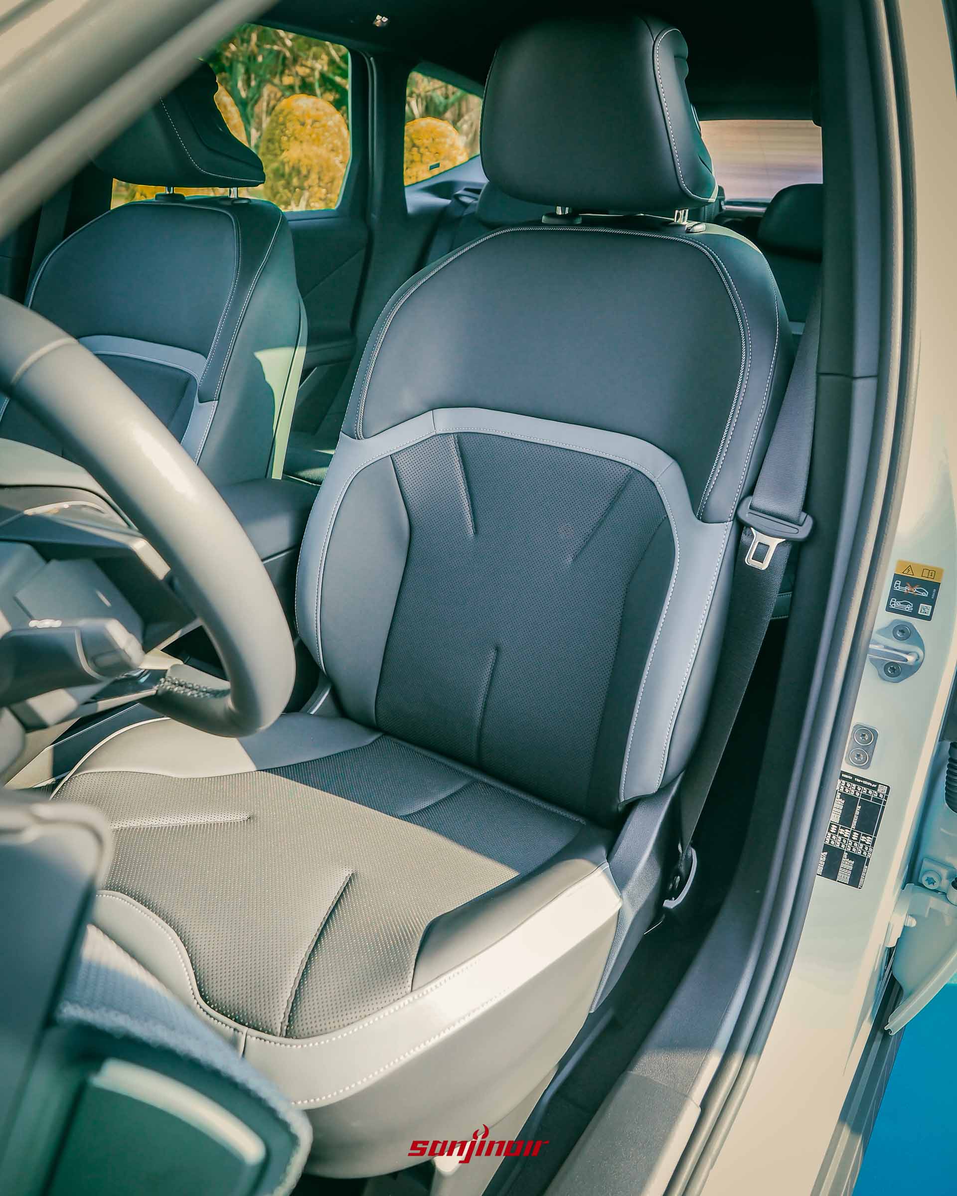 BMW iX3前排座椅特寫，展示深色皮質、透氣孔洞以及淺色縫線與拼條的細節設計。