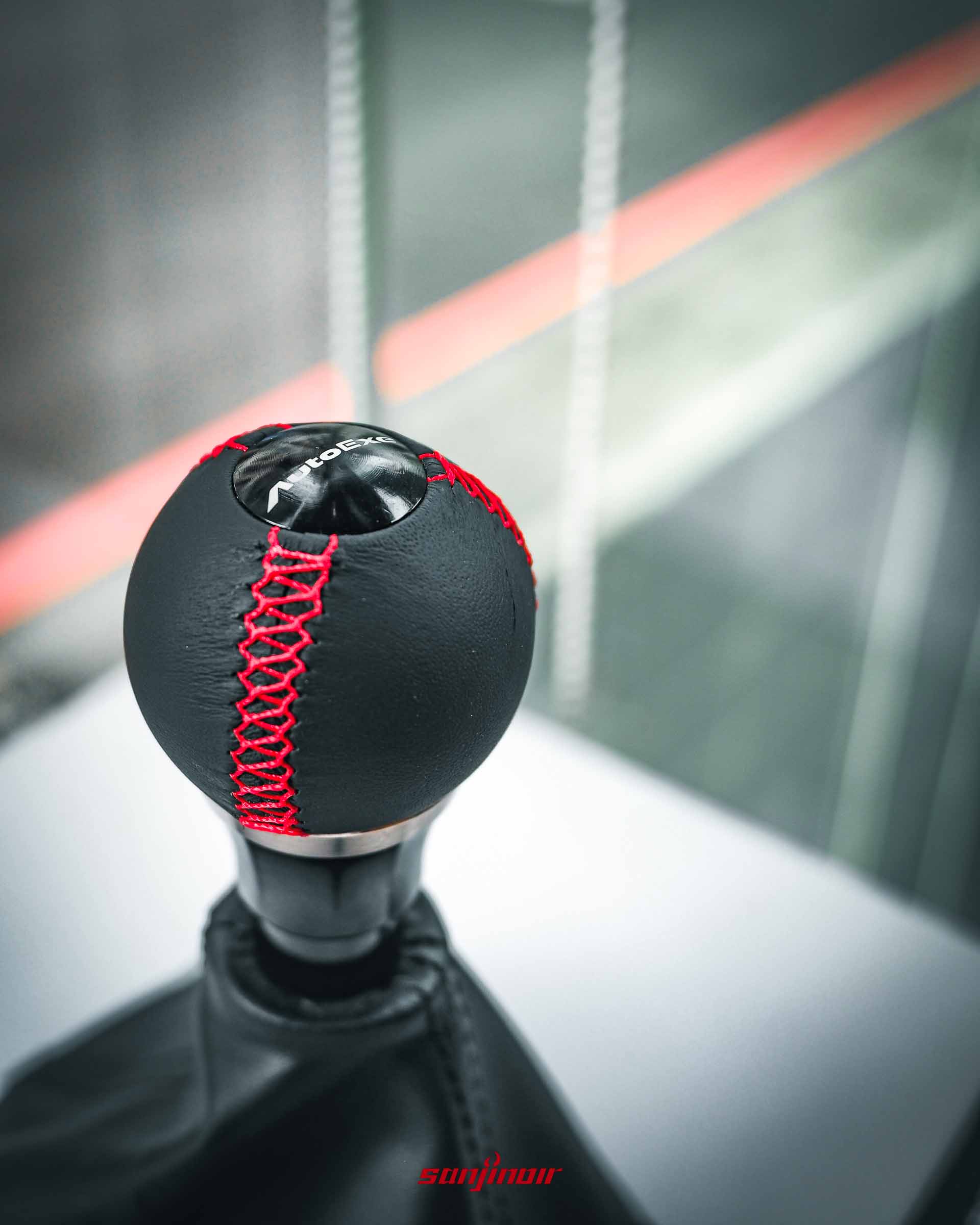 AutoExe 真皮球型排檔頭近距離特寫，清晰可見頂部 AutoExe 雷射雕刻字樣與精緻的紅色手工縫線。