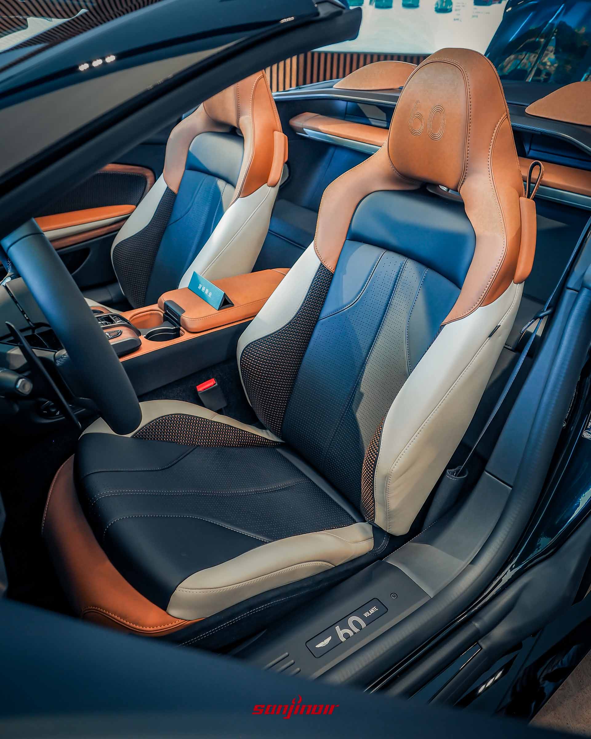 Vanquish Volante 60th Anniversary Edition 座椅細節，展示馬鞍棕頭枕上的 60 週年刺繡（由 2500 針、16m 絲線組成）和象牙白編織皮革紋理。門檻上有 60th Volante 徽飾。