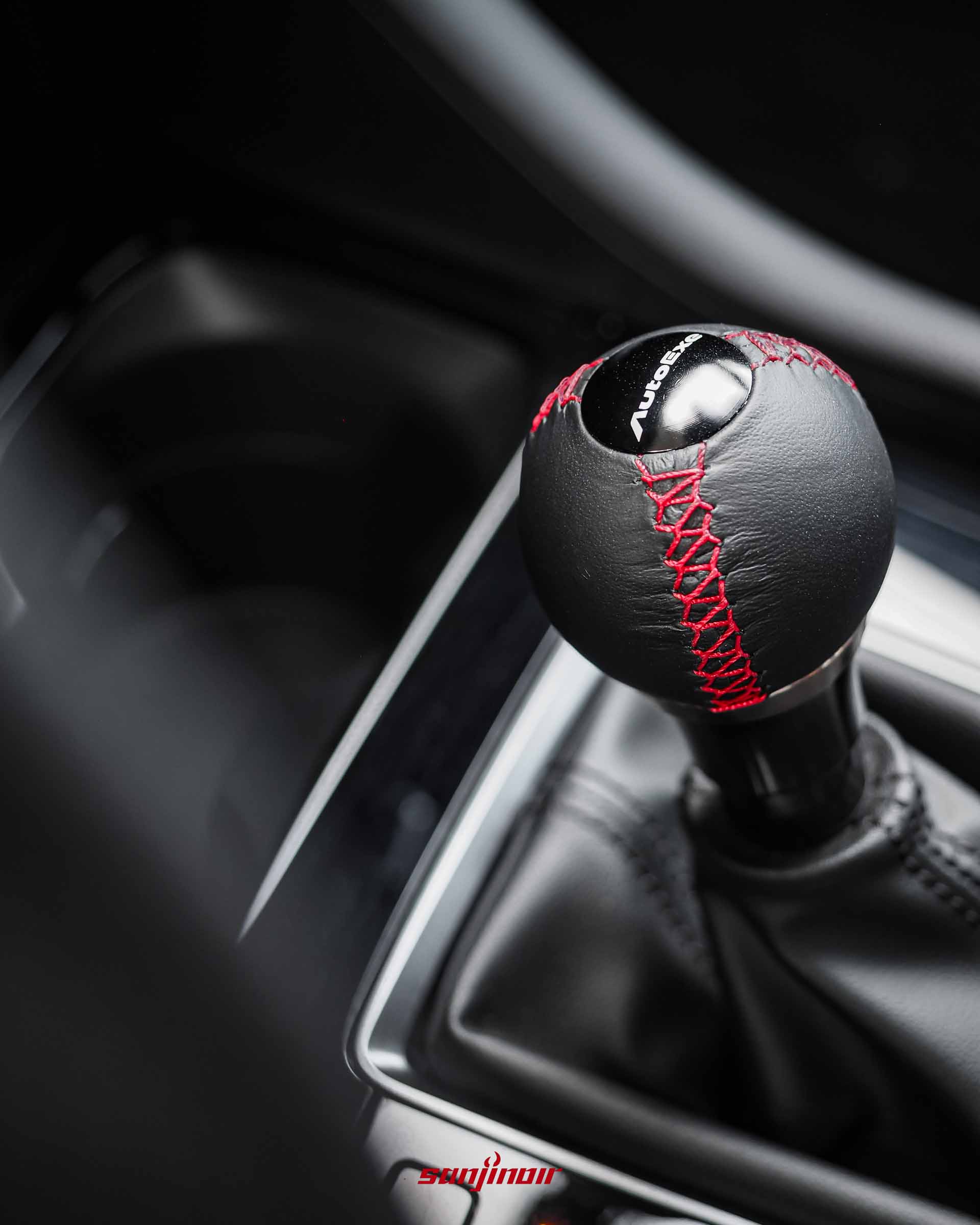 黑色真皮球型排檔頭，有紅色縫線，刻有AutoExe標誌。