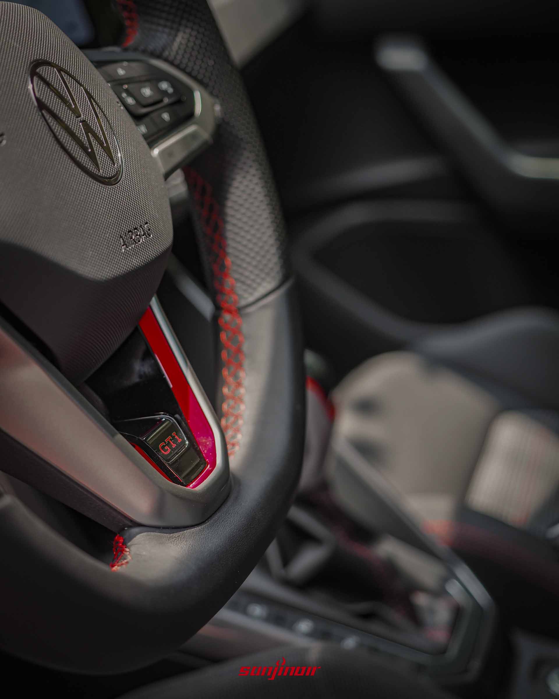 2026 Volkswagen Polo GTI方向盤底部的GTI專屬銘牌與紅色縫線特寫。