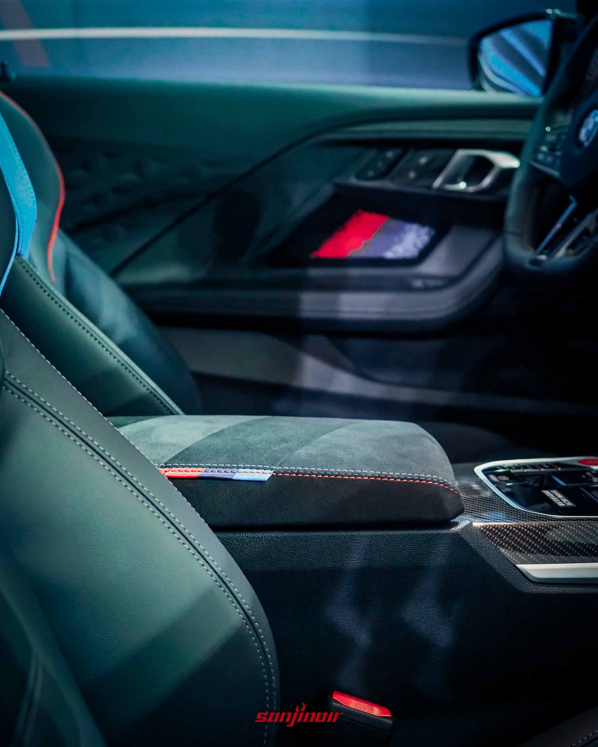 BMW M2內裝中央扶手特寫照，採用Alcantara麂皮材質包覆，側邊帶有經典M三色縫線裝飾。