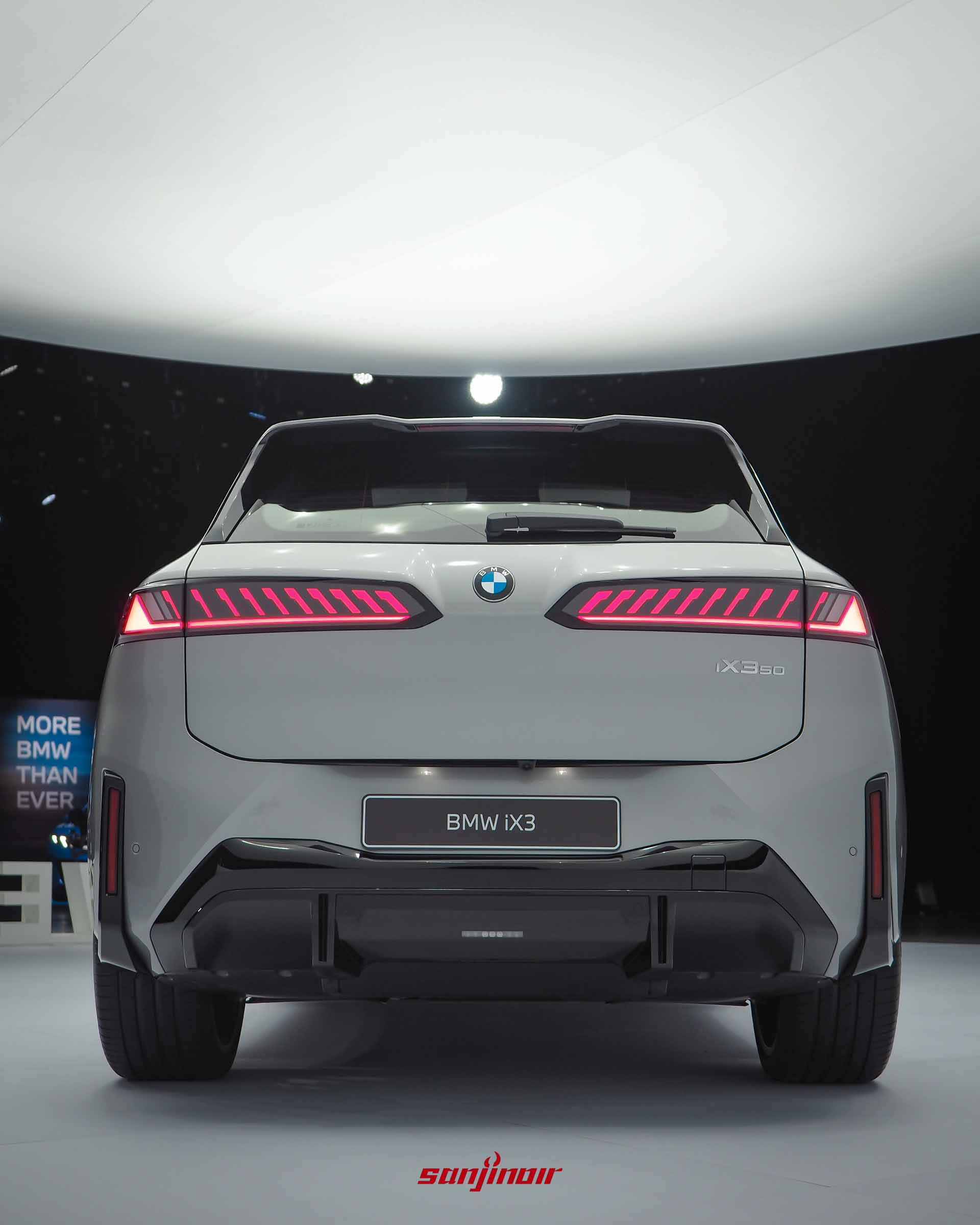 BMW iX3的正車尾視覺,發光的斜向紅色尾燈光條橫跨左右,下方為黑色的下擾流板。