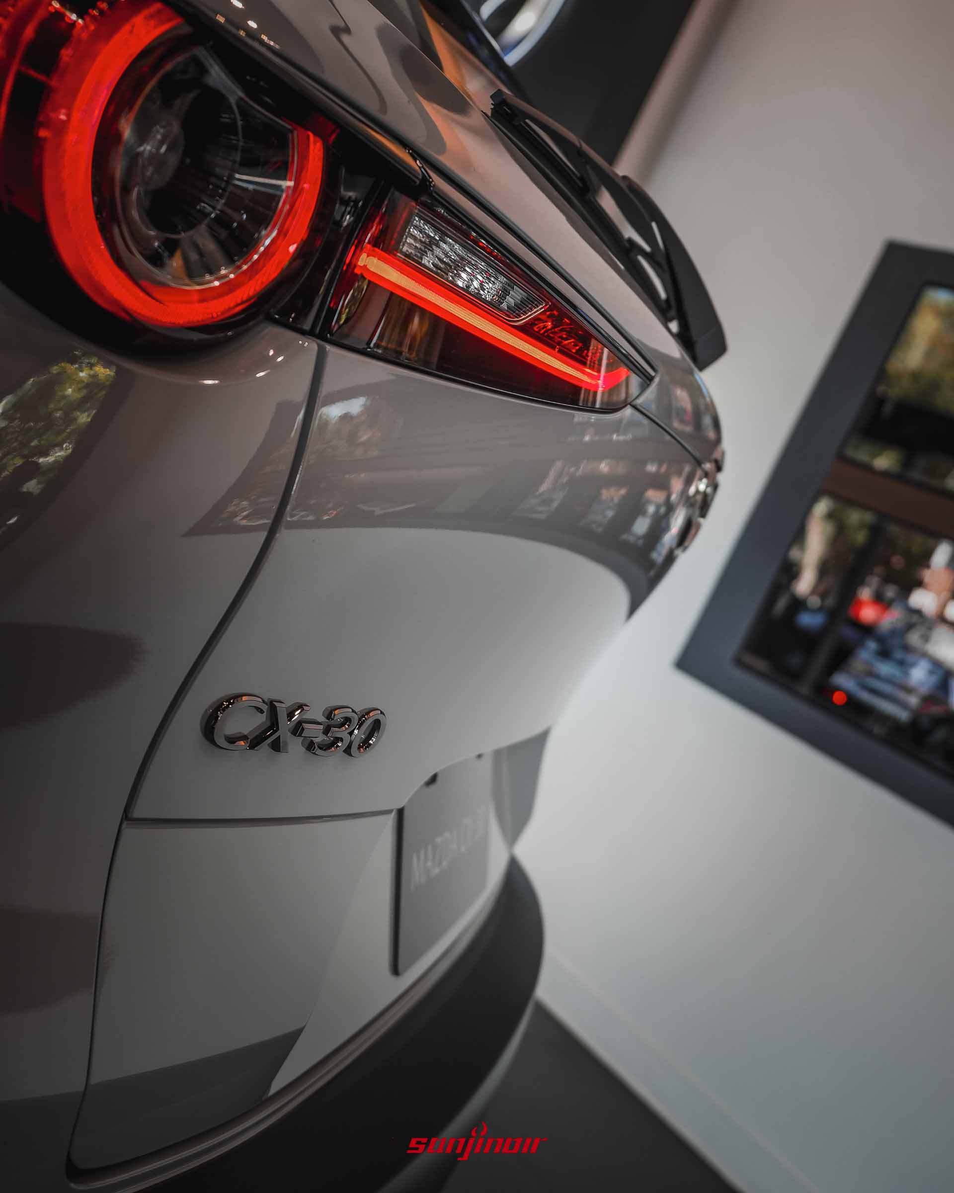 特寫MAZDA CX-30 Air Edition車尾右側亮起的LED尾燈,以及下方的黑化CX-30字樣銘牌。