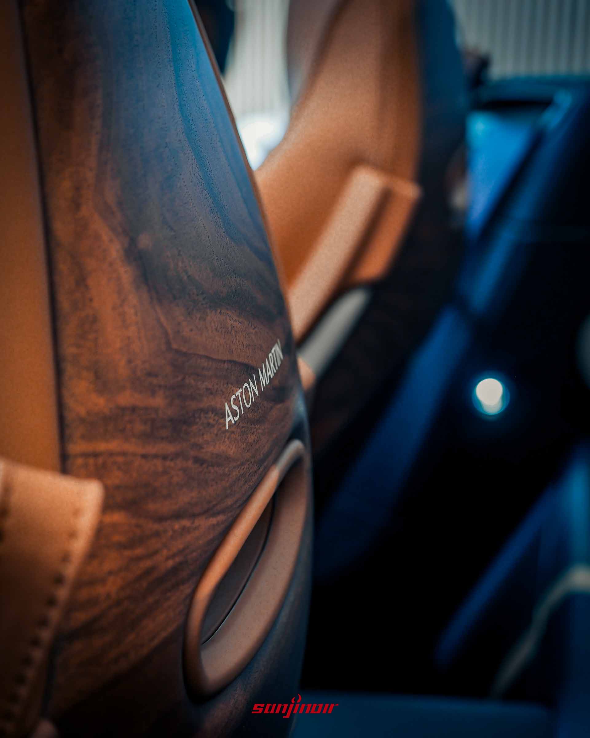 Vanquish Volante 60th Anniversary Edition 椅子背後細節，展示深色胡桃木椅背飾板，上方有 Aston Martin 金屬字樣和皮革拉環。