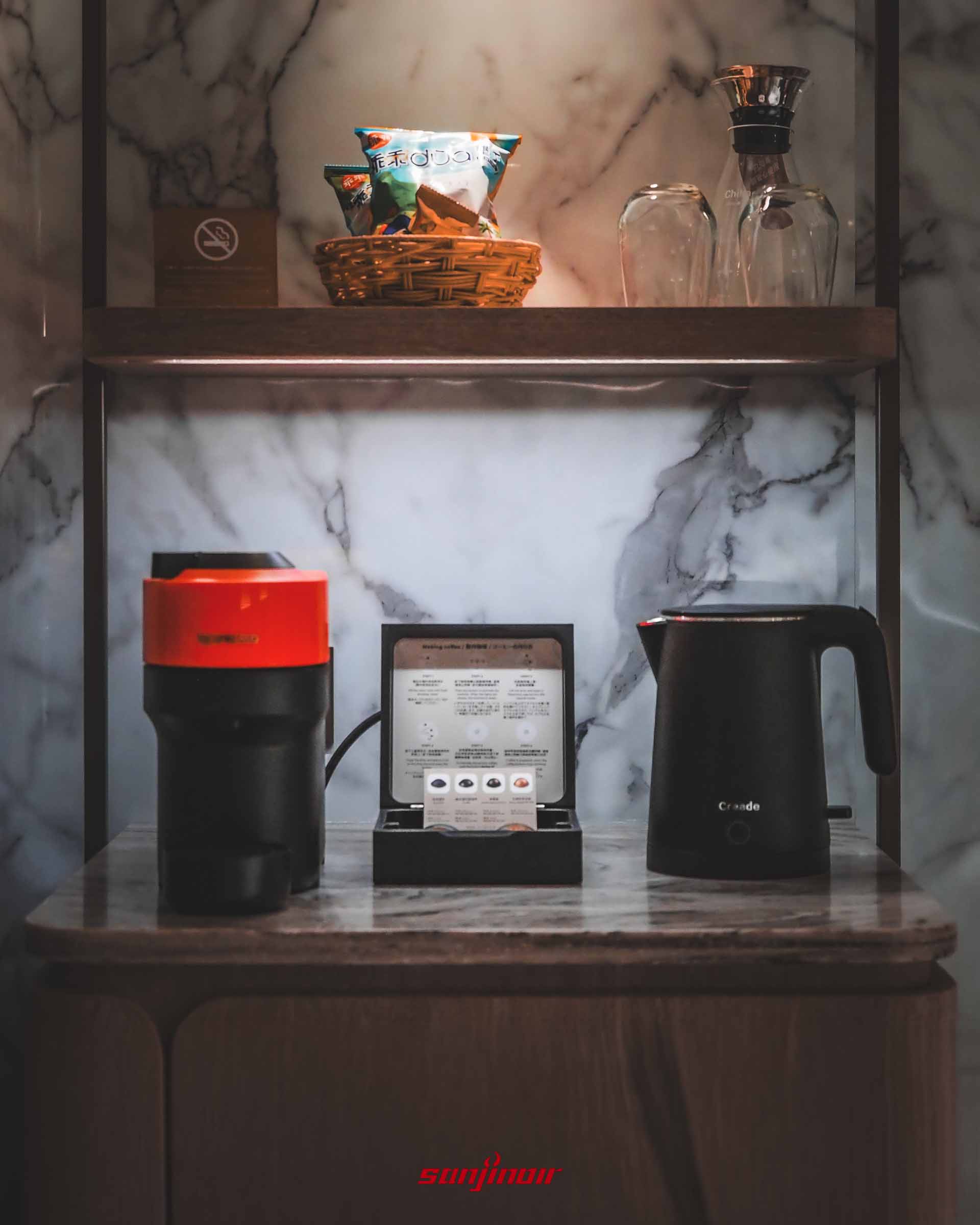 客房內的茶水檯,擺放著膠囊咖啡機、黑色熱水壺與編織籃裝的零食。