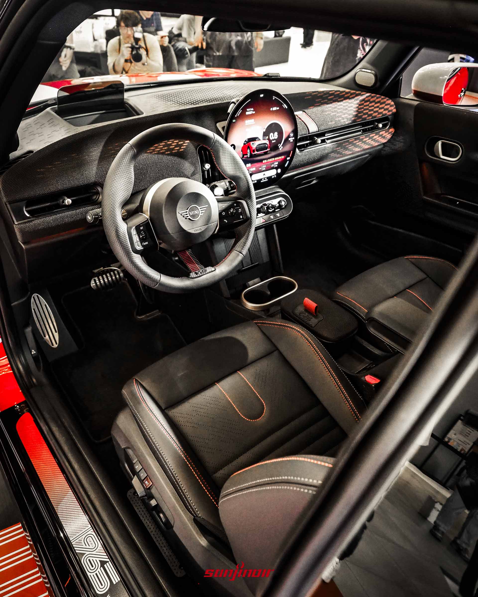 MINI 1965 Victory Edition的駕駛座艙全景,包含方向盤、中央圓形顯示螢幕以及副駕駛座前方的獨特紋理飾板。