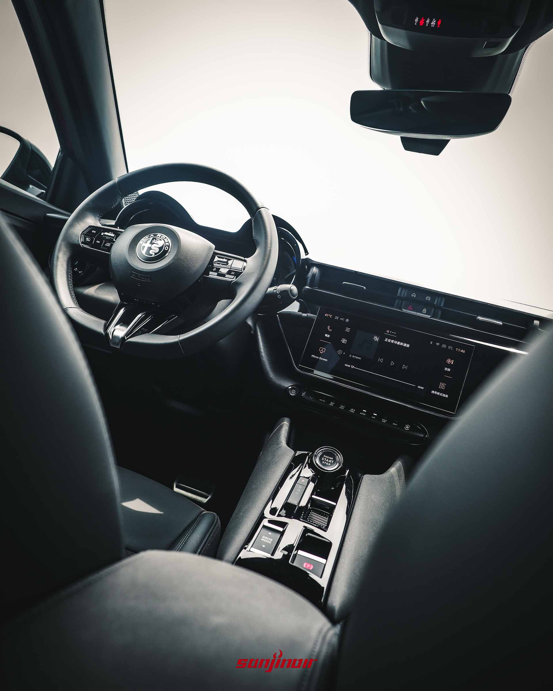 Alfa Romeo Junior前座內裝全景,從後座視角拍攝,展示多功能方向盤、數位儀錶、中央觸控螢幕與鞍座按鍵。