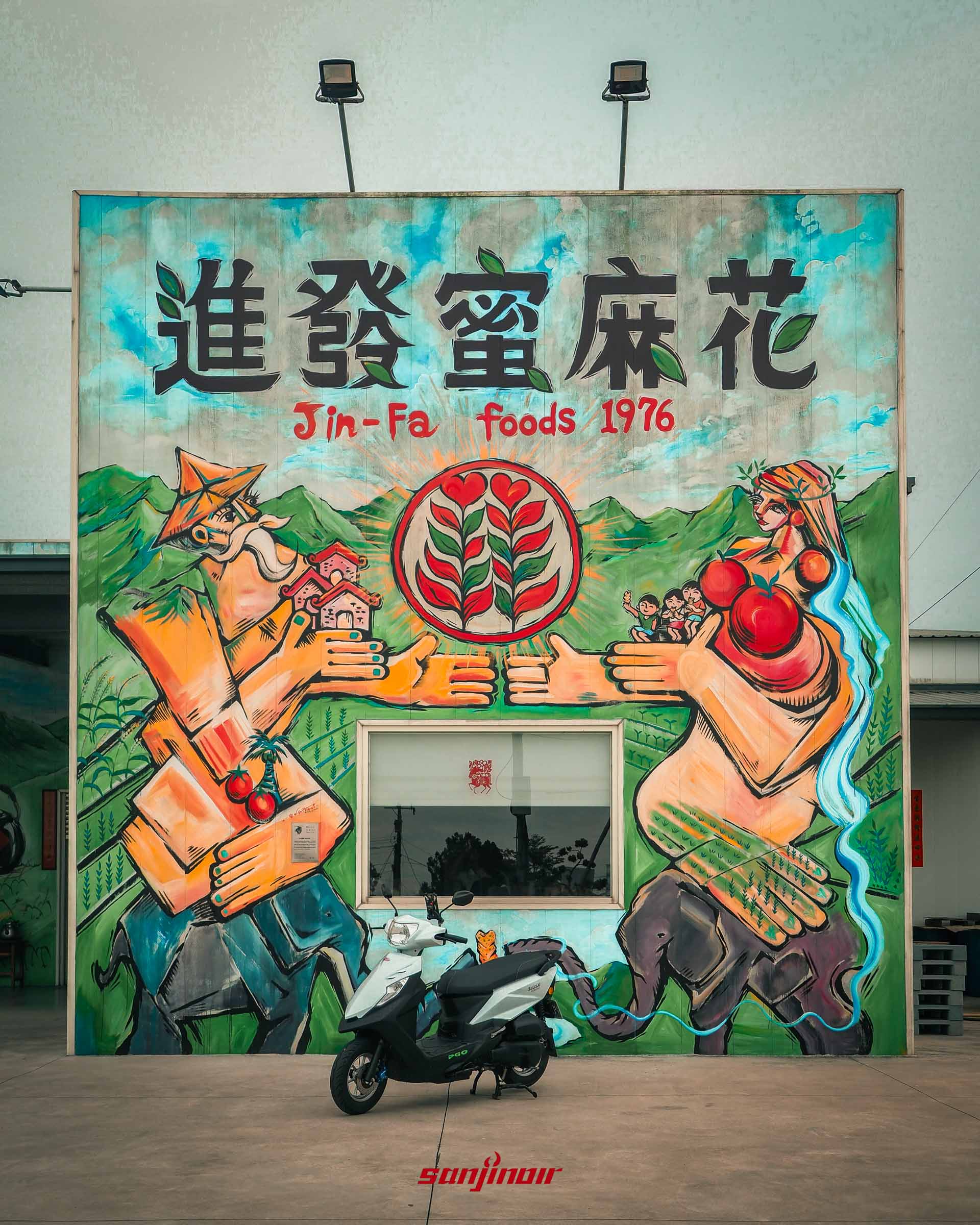 白色PGO isavR威力125停放在進發蜜麻花的巨大手繪品牌壁畫前方。