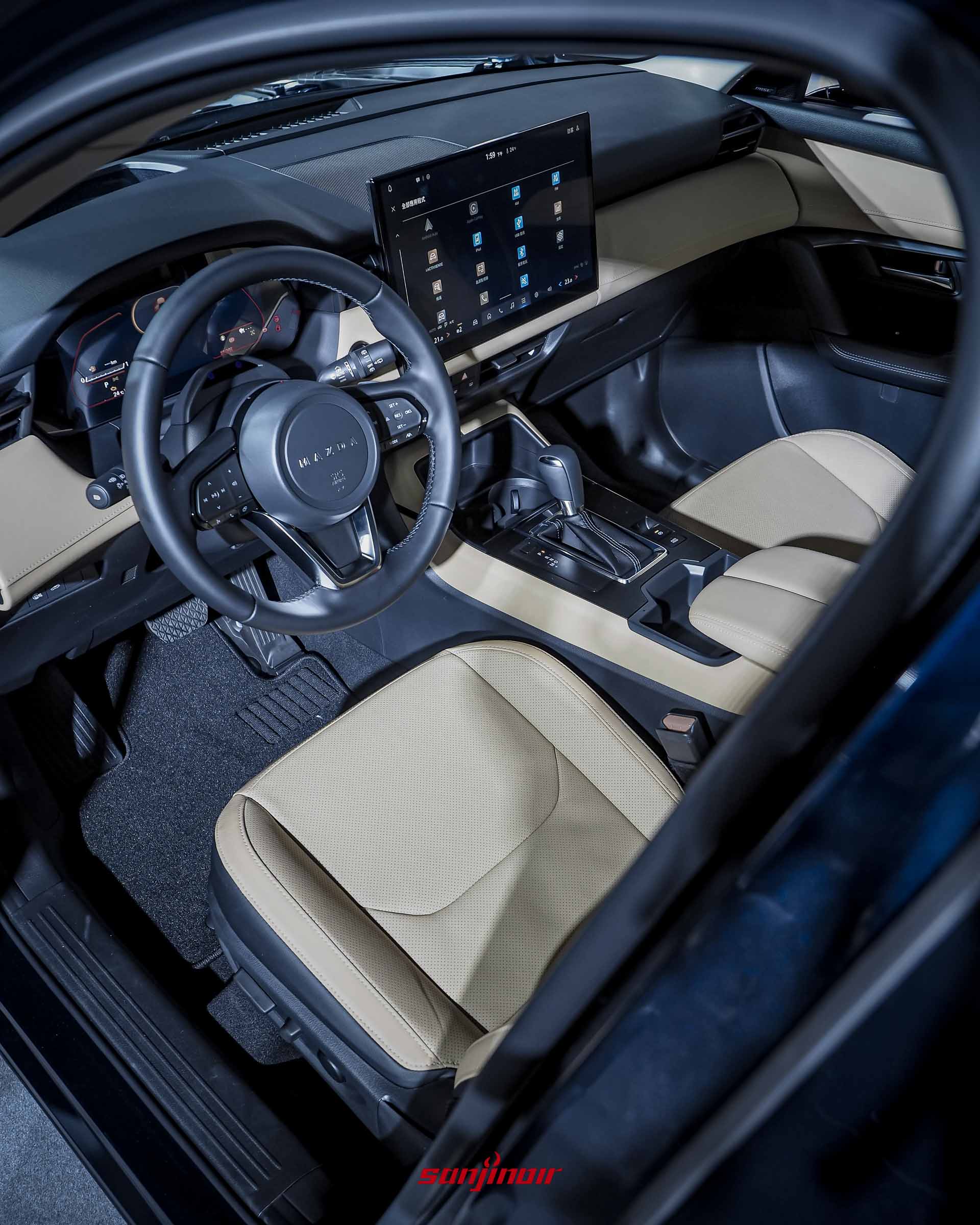 MAZDA CX-5駕駛座與中控台俯視圖，展示荒漠棕內裝、皮質方向盤、數位儀錶板與中央大型觸控螢幕。