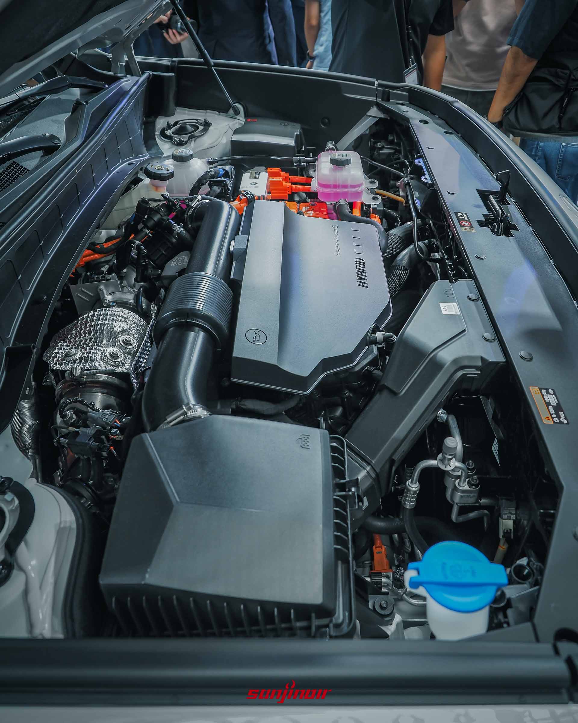 2026 Hyundai Palisade引擎室內部特寫，中央黑色飾蓋印有HYBRID字樣，並可見周圍的橘色高壓電線組與各項機械部件。