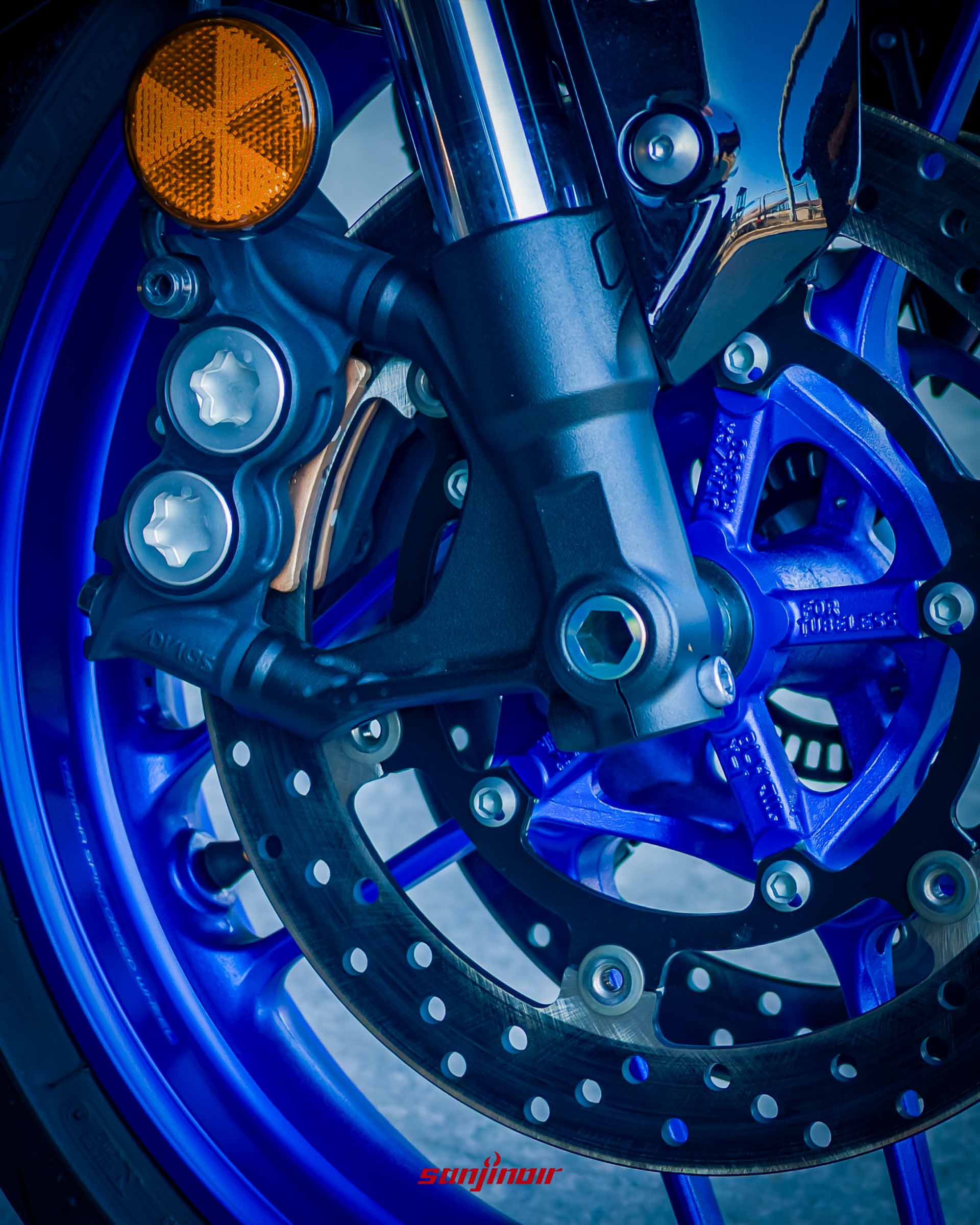 藍色Yamaha YZF-R7的前煞車系統特寫,包含黑色的輻射卡鉗、打孔碟盤與藍色的輕量化輪圈。