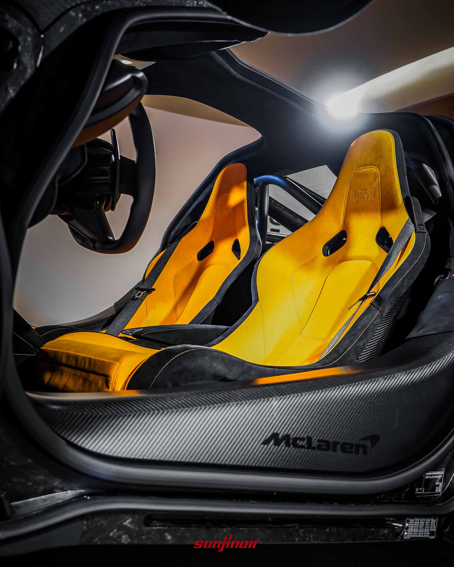 McLaren 750S Le Mans車室內裝側拍,兩張亮橘黃色的碳纖維賽車桶椅,配有黑色安全帶與深色麂皮內裝細節。