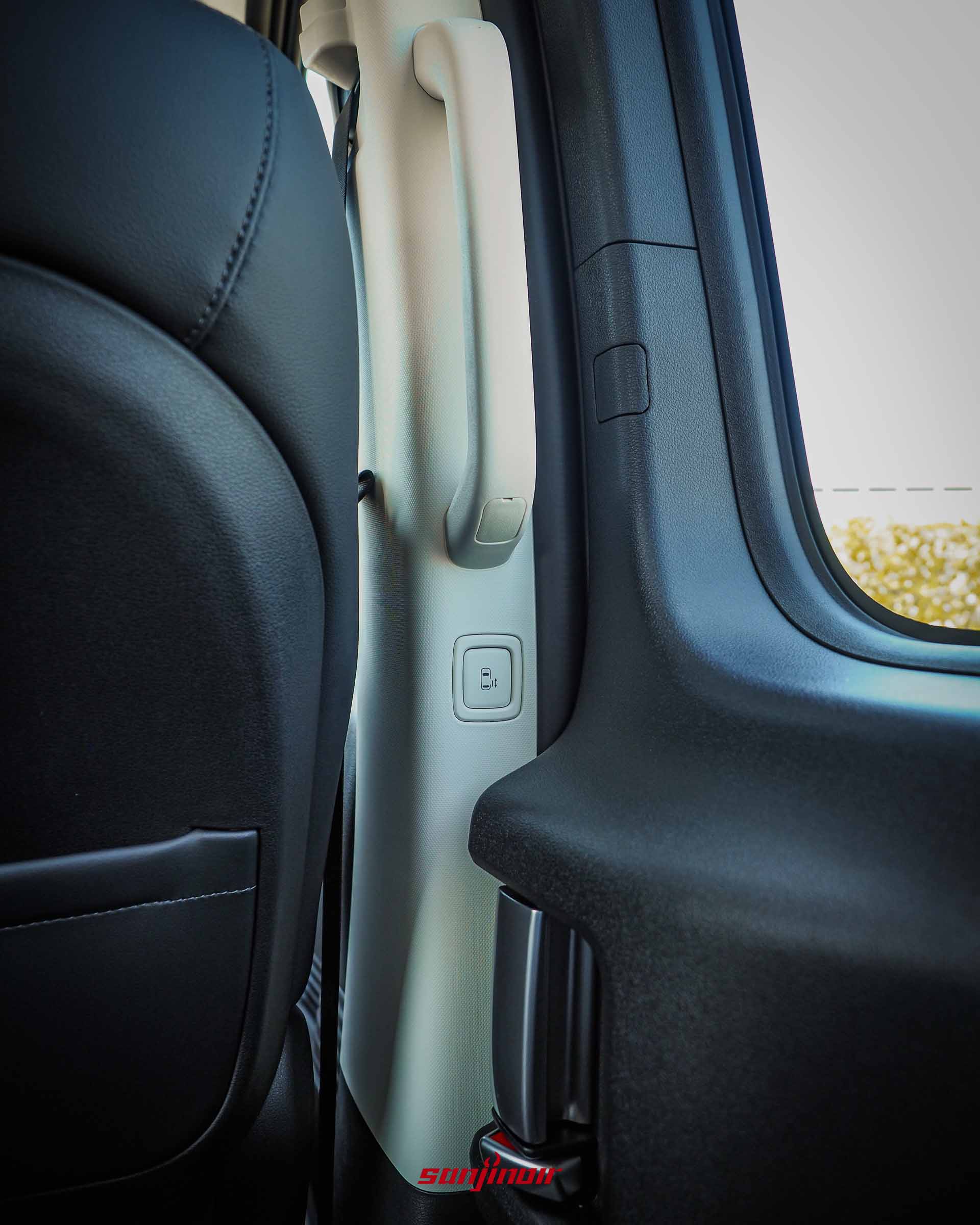 特寫 Hyundai Staria 車廂內部 B 柱,展示供後座乘客使用的電動滑門開關按鍵與大型登車扶手。