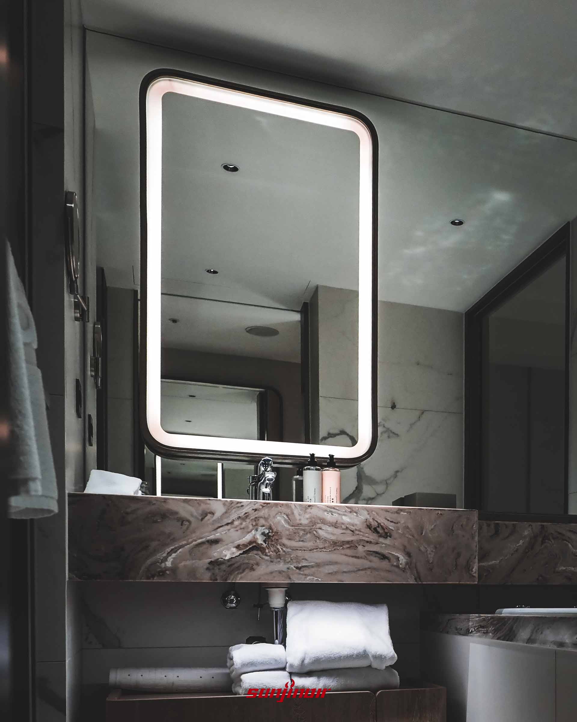 浴室洗手檯,大理石檯面上方設有一面帶有發光燈條的長方形鏡子。