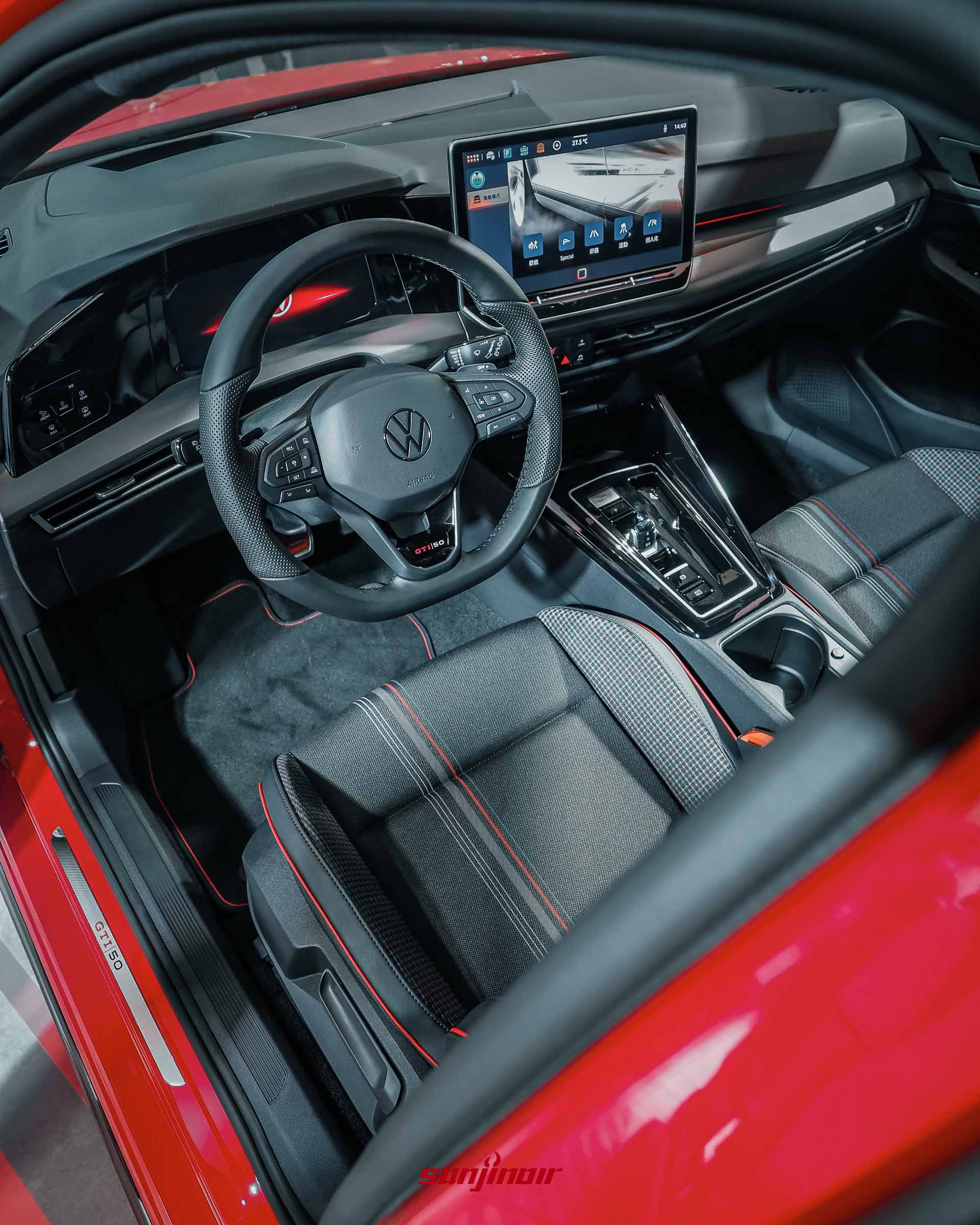 從右前車門視角拍攝的Golf GTI EDITION 50內裝全景，展示數位儀表、12.9吋中控螢幕、黑化方向盤與格紋跑車座椅。