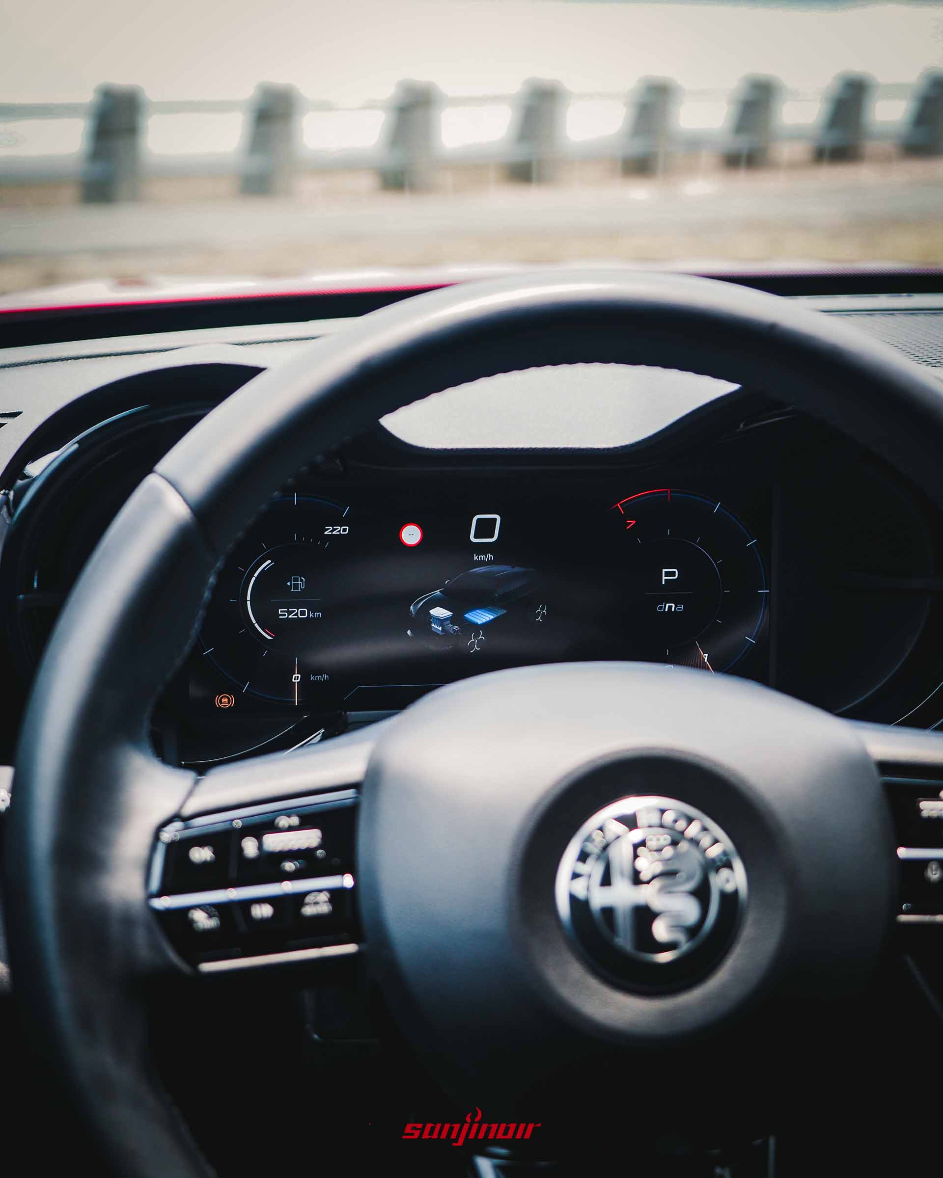 Alfa Romeo Junior駕駛座儀錶板特寫,顯示10.25吋全數位儀錶內的油電動能監測畫面,前方有模糊的方向盤廠徽。