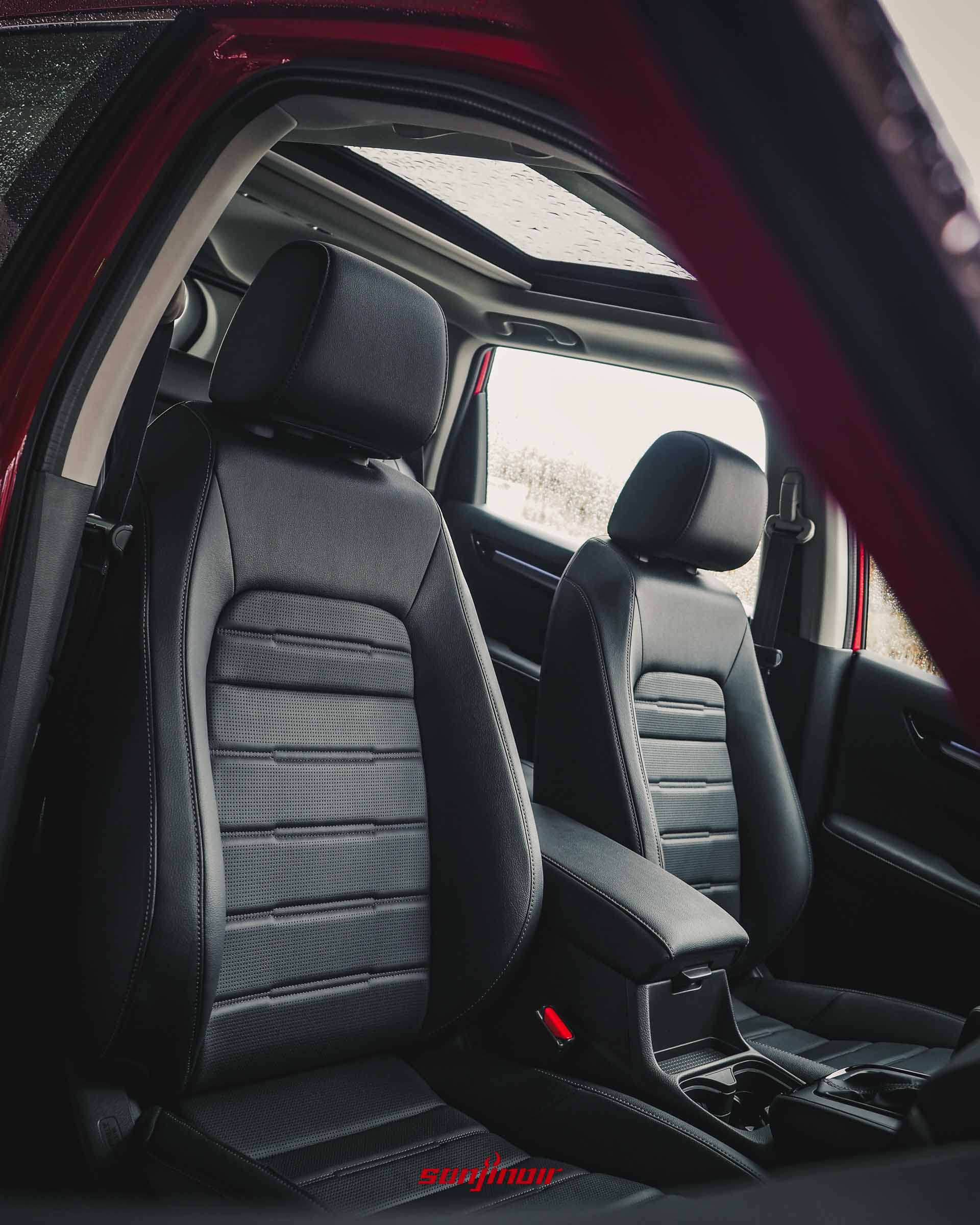 從副駕駛座開啟的車門向內觀看HONDA CR-V的雙前座黑色皮質通風座椅,上方可見全景天窗透進的光線。