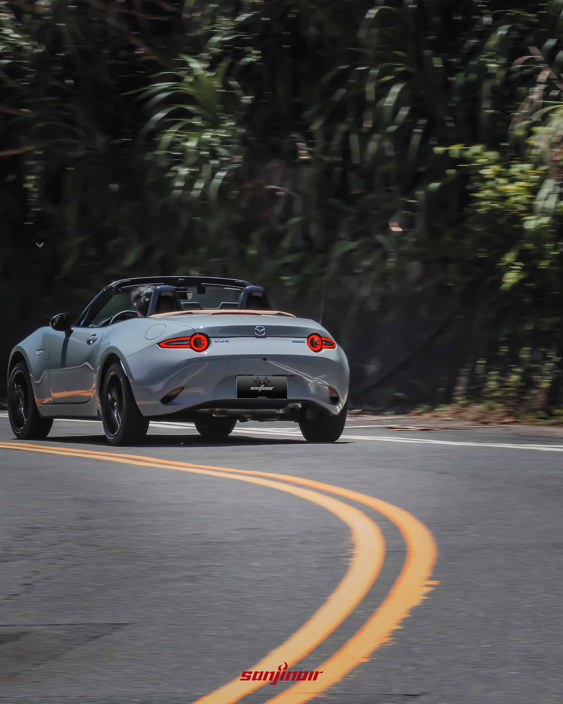 動態追焦攝影,灰色MAZDA MX-5 RS於山林彎道中疾駛的車尾視角,經典雙圓形尾燈亮起。