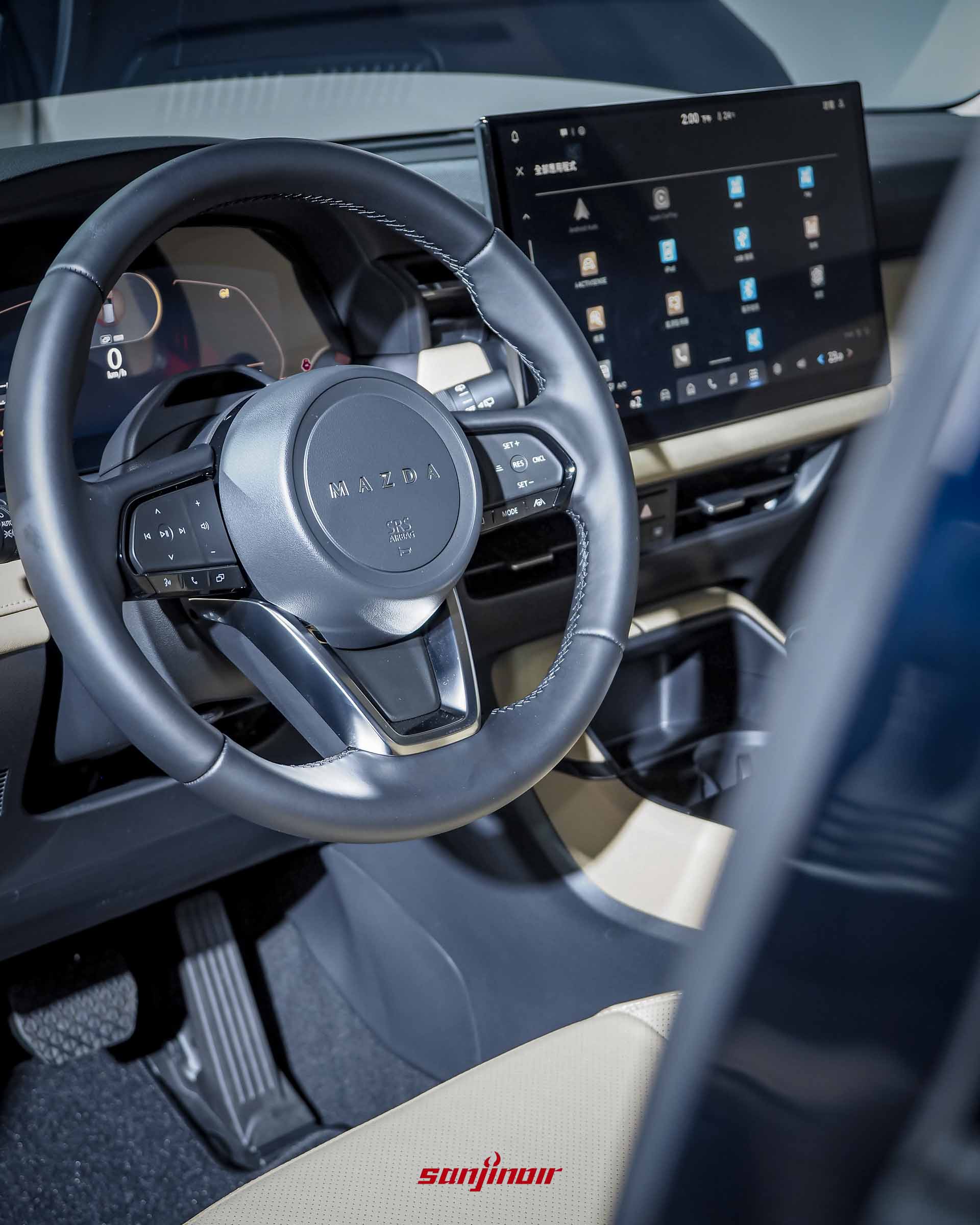 MAZDA CX-5方向盤與中控螢幕特寫，螢幕上顯示著包含Apple CarPlay等應用程式的網格選單。