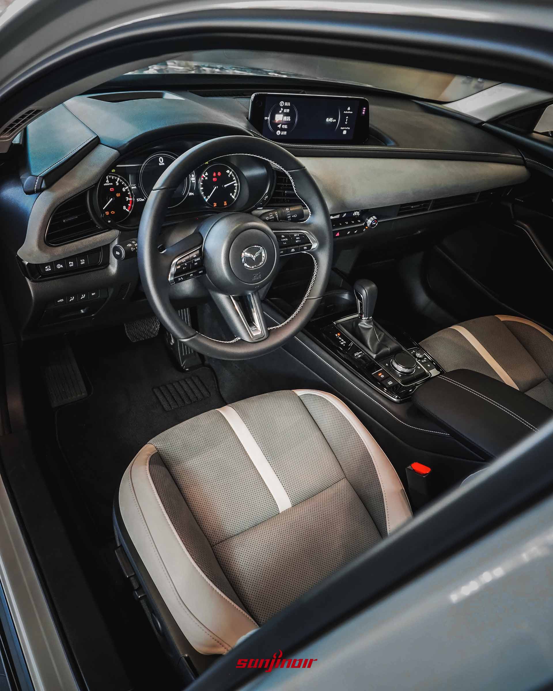 從副駕駛座窗外視角拍攝的MAZDA CX-30 Air Edition前座內裝全景,包含真皮方向盤、數位儀錶板、懸浮式中控螢幕與排檔座。