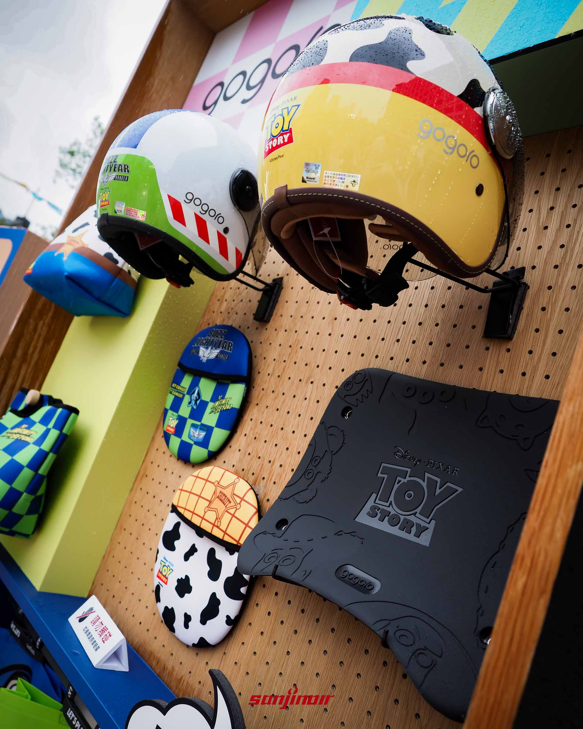 Gogoro玩具總動員聯名配件展示牆，包含巴斯光年與翠絲造型安全帽、巧納袋與三眼怪防滑踏墊。