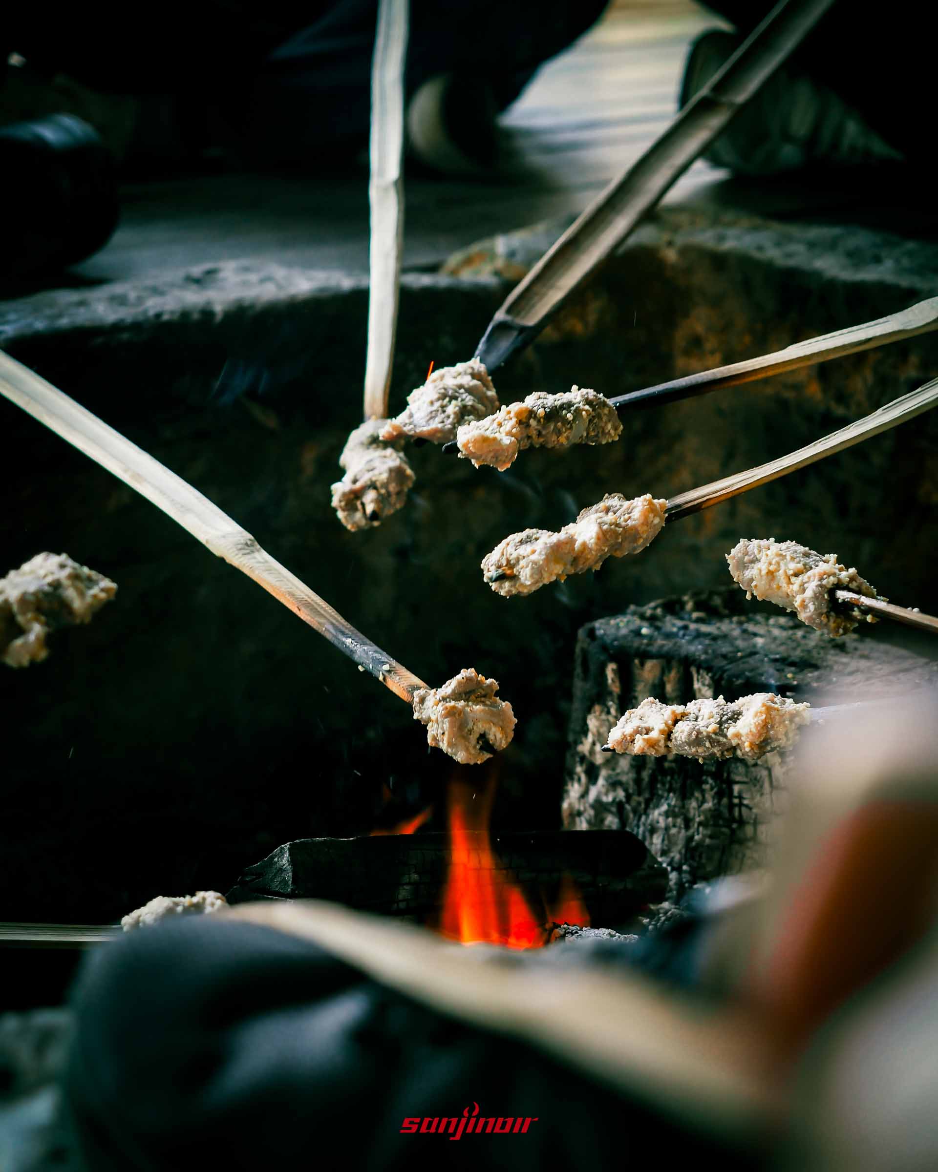 營火上烤著串在竹籤上的醃漬山豬肉。