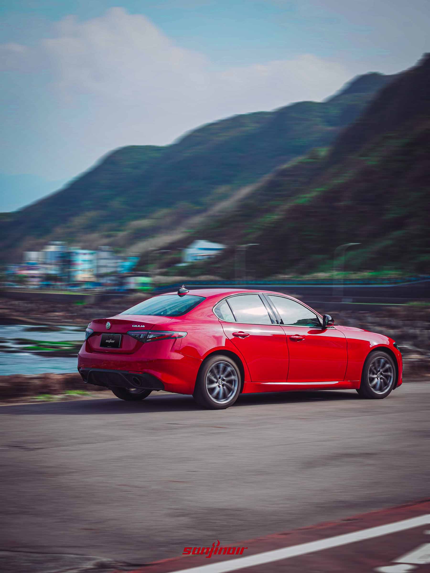 Alfa Romeo Giulia Sprint於海岸公路疾駛的動態追焦照,展現車體流線與動態速度感。