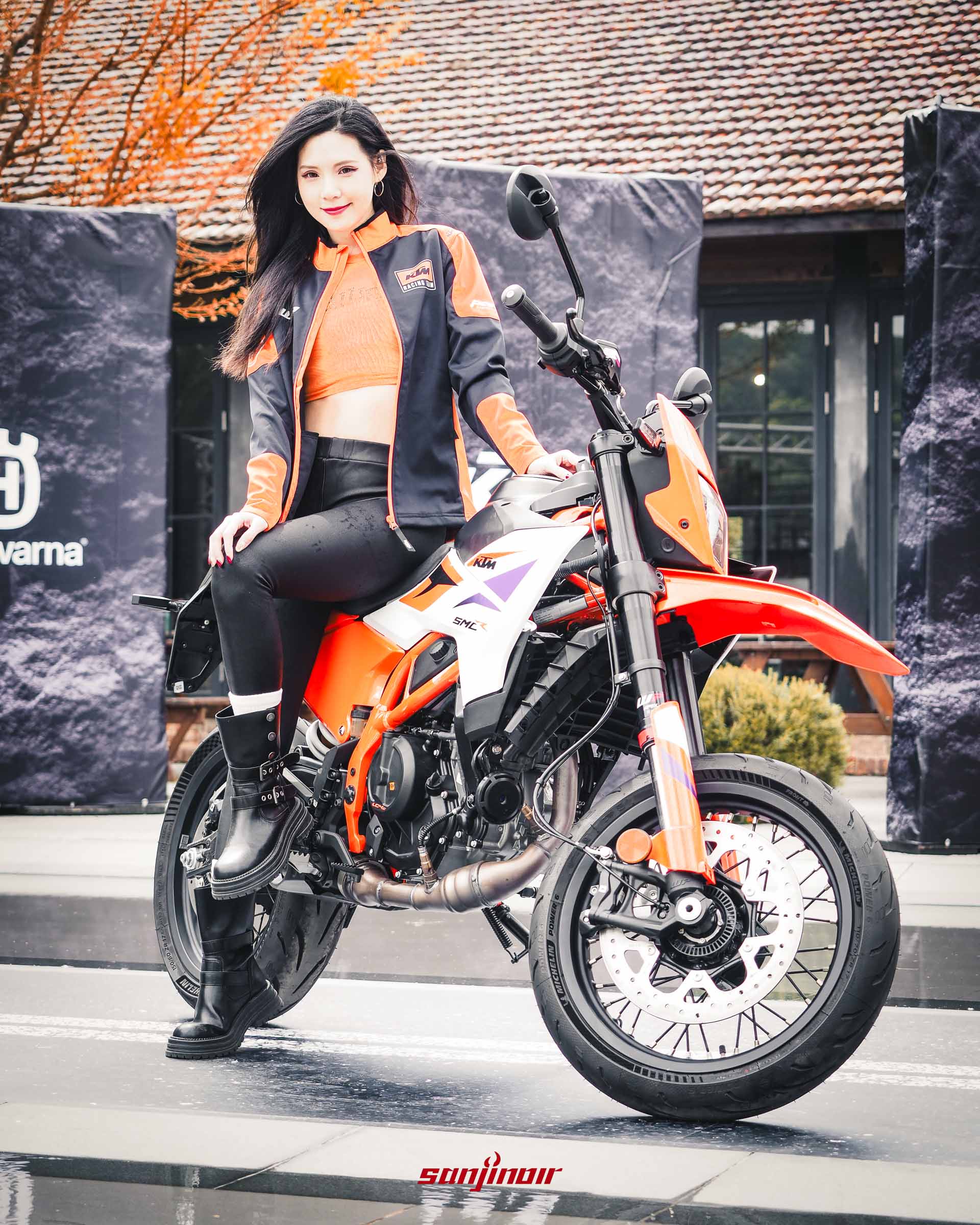 模特兒DuDu坐在KTM 390 SMC R摩托車上，車身採用橘白黑三色塗裝，展示強烈的滑胎車風格。