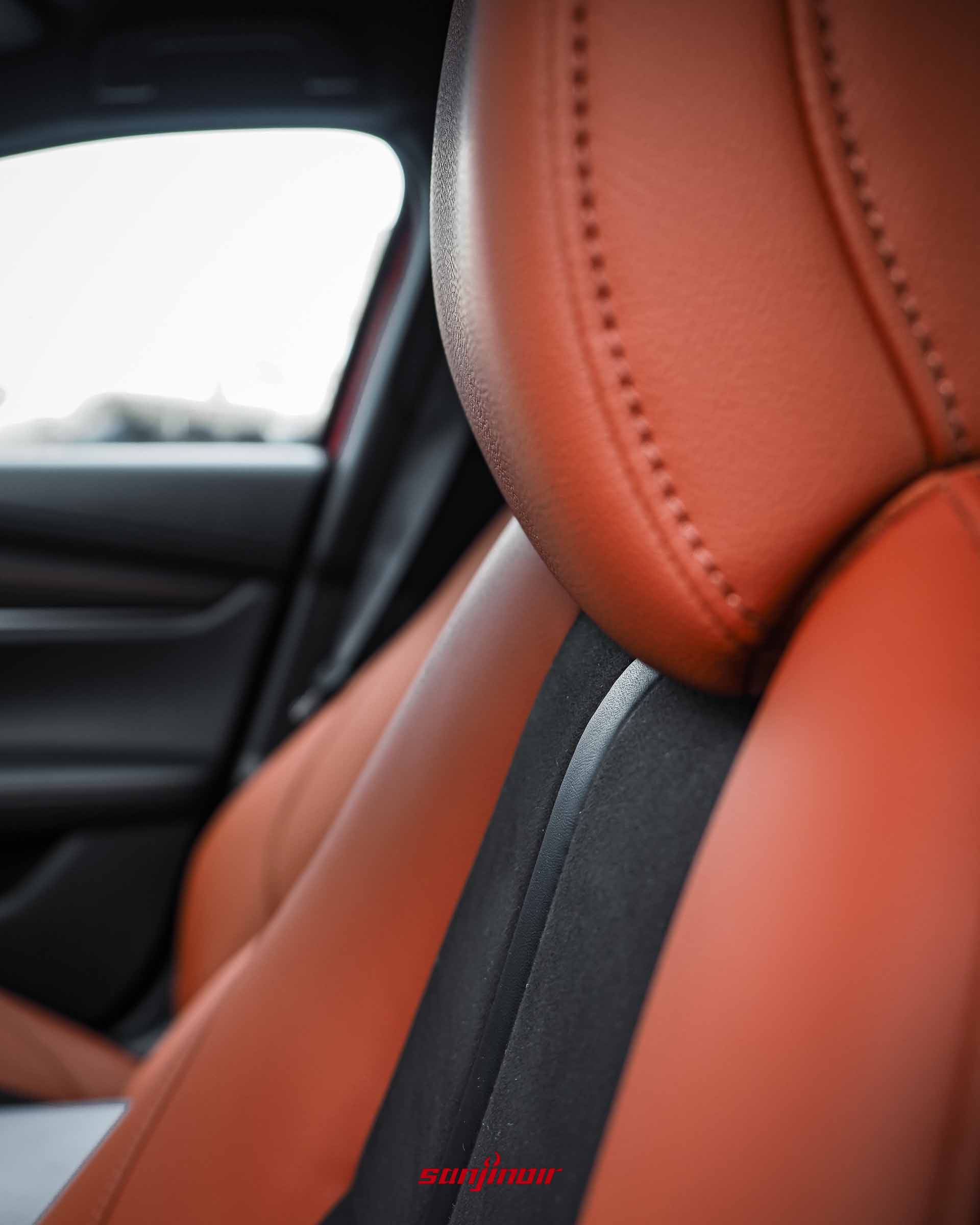 MAZDA3 HOMURA車內座椅特寫，展示赤陶紅皮革與黑色麂皮拼接材質，並帶有精緻的車縫線。