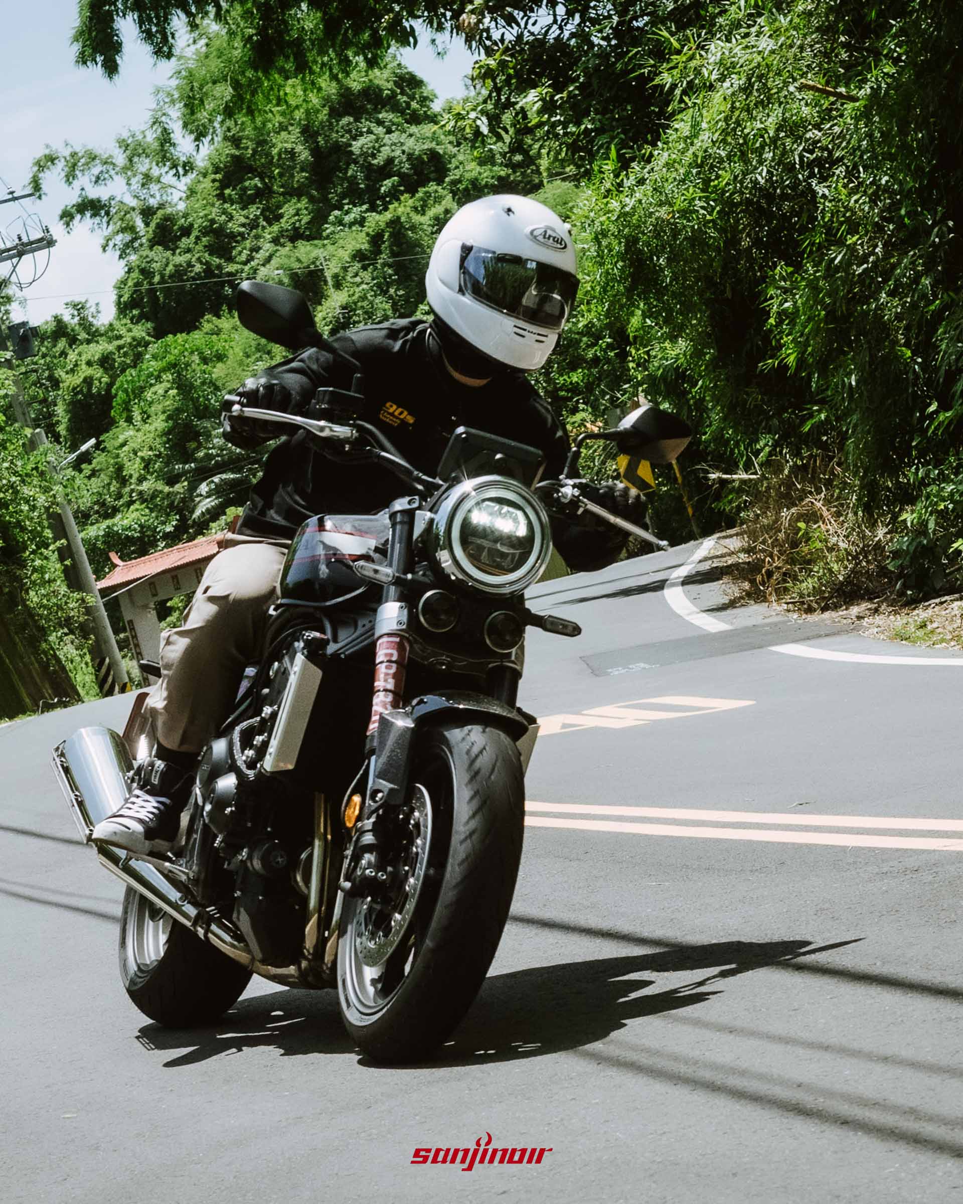 騎士騎乘Honda CB1000F於山路下坡過彎時的車頭正面特寫動態追焦照片。