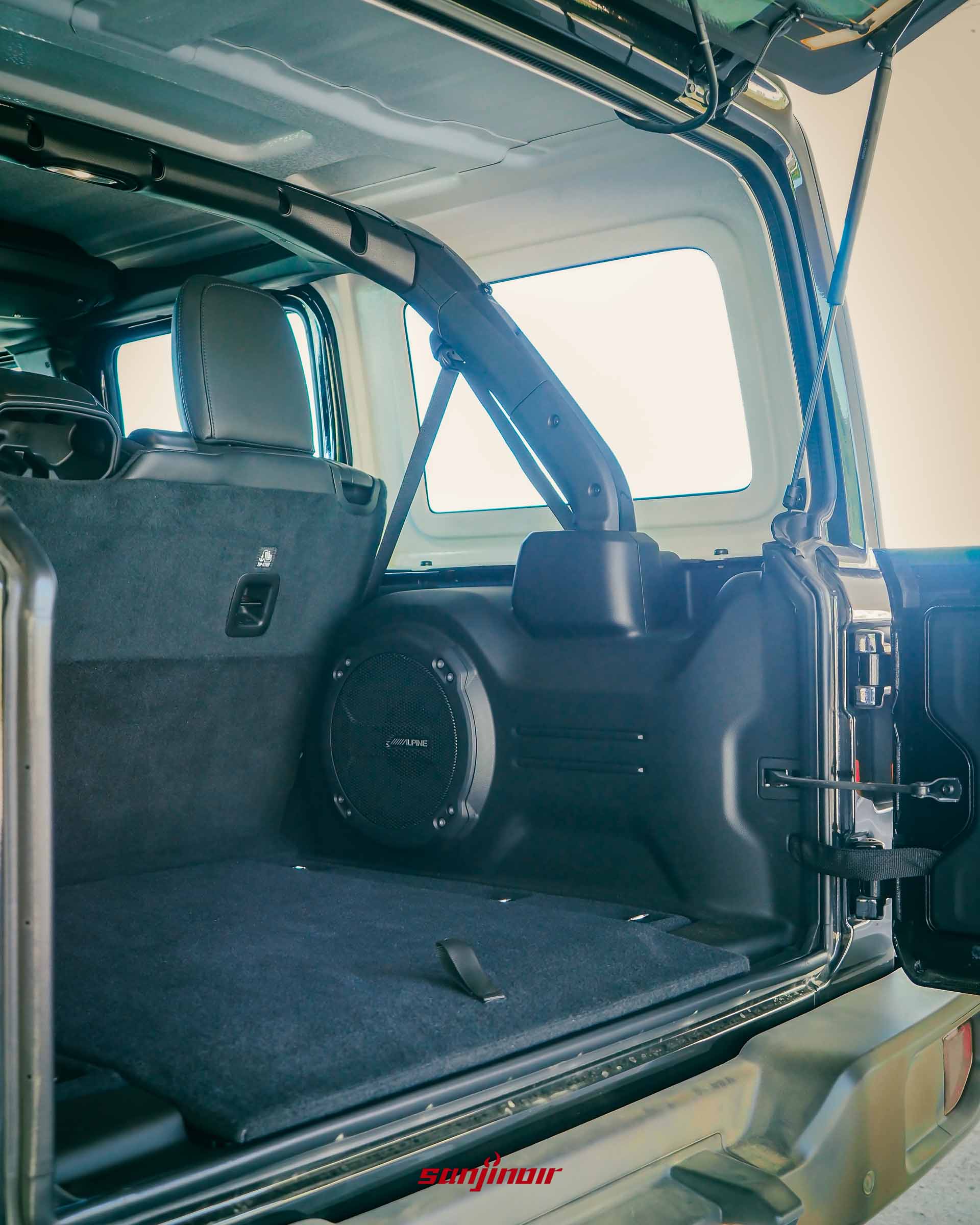 Jeep Wrangler Sahara 打開尾門的後車廂空間,可見平整的底板、右側的 Alpine 重低音喇叭與外露的防滾籠結構。
