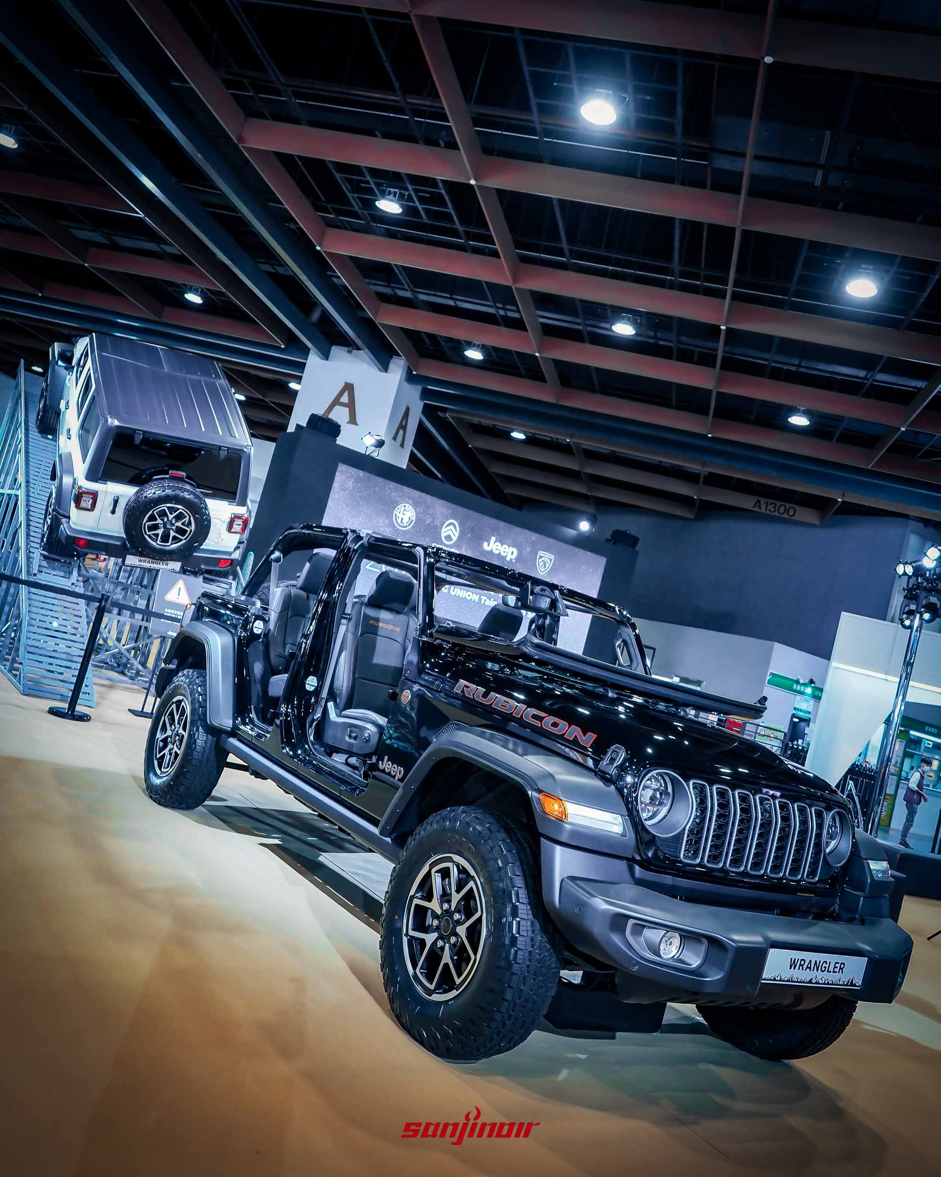 黑色Jeep Wrangler越野車展示於斜坡造景前，車門為開啟狀態，展示內裝。