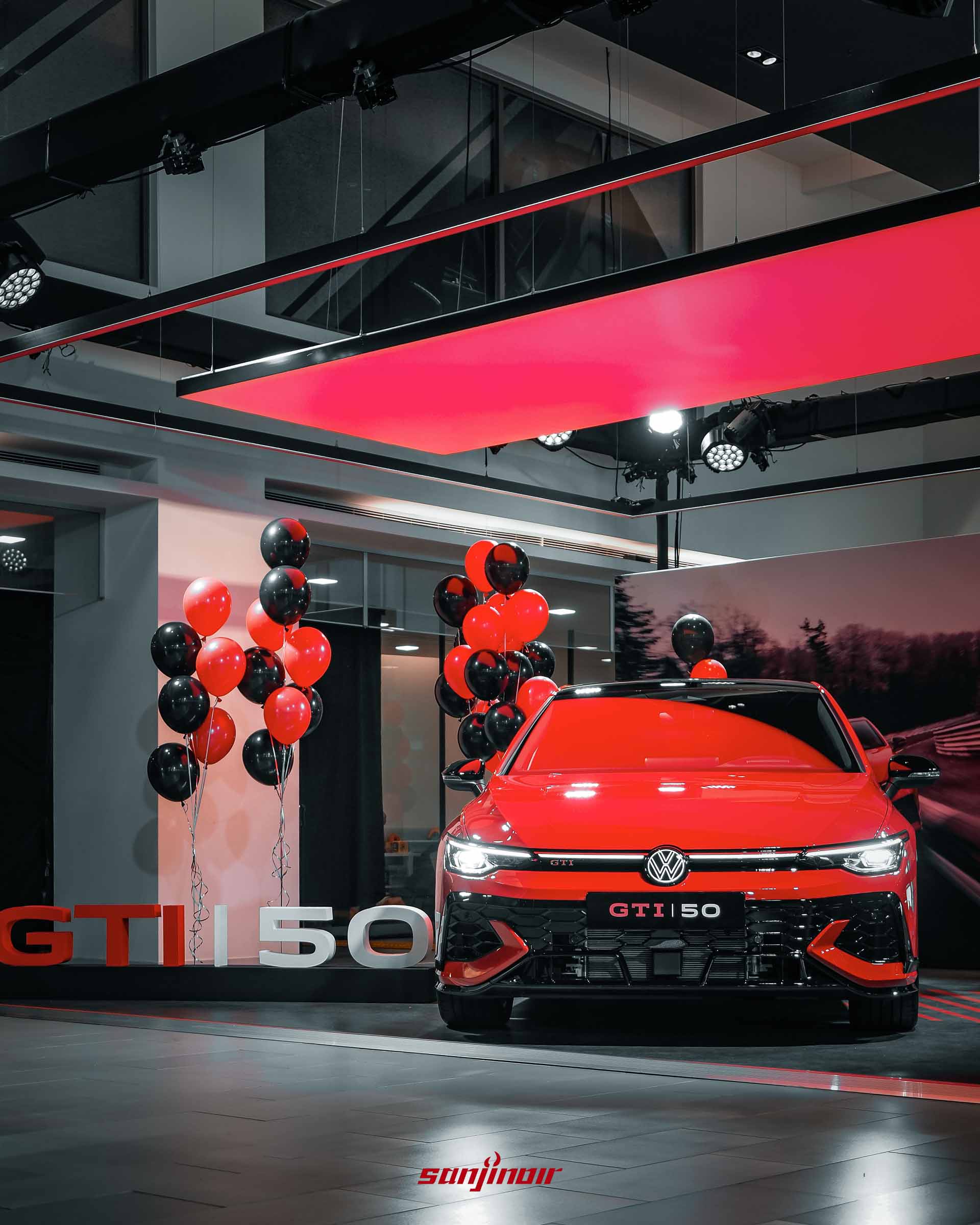 紅色Golf GTI EDITION 50於發表會現場的車頭正面照，周圍佈置有紅黑氣球，車前放置大型GTI 50立體字樣裝飾。