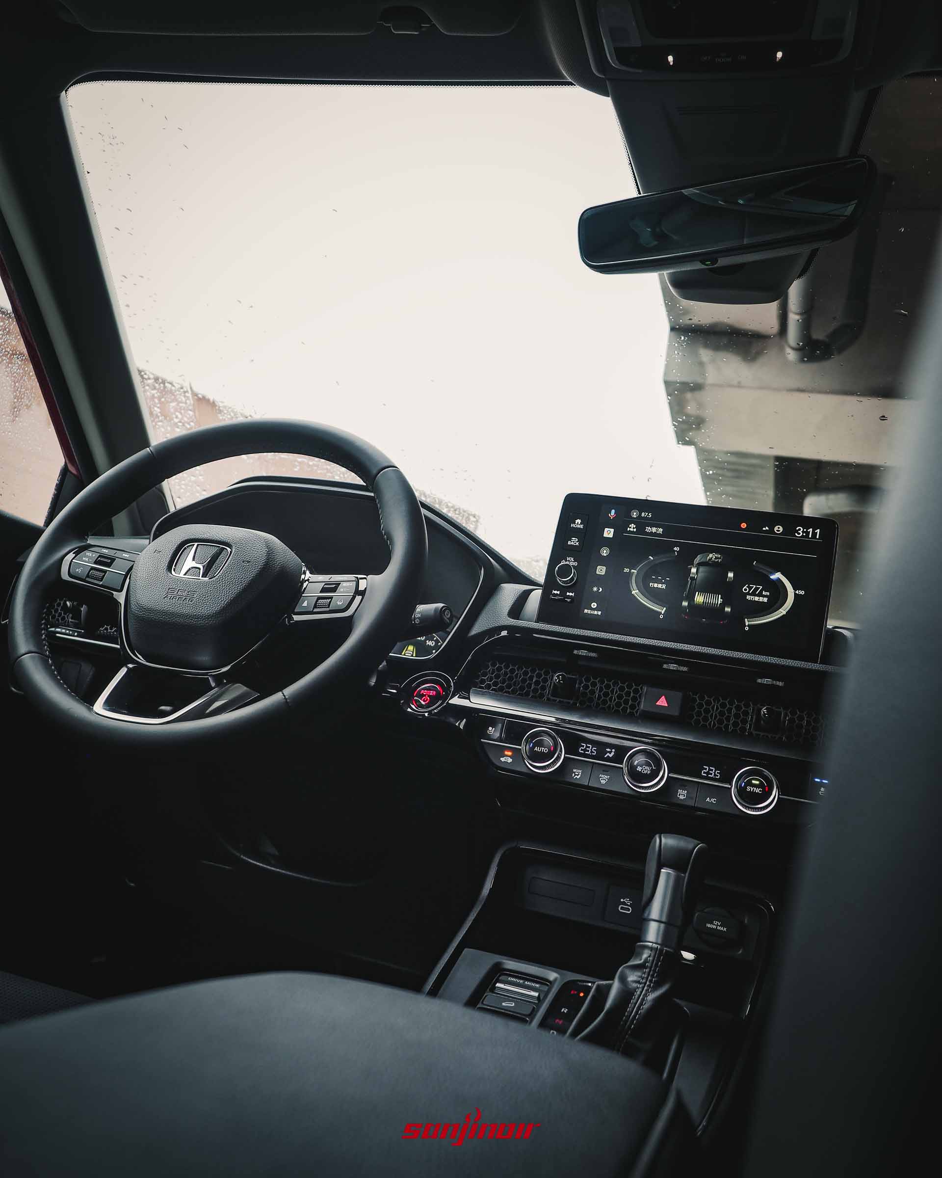 從後座中央向前觀看HONDA CR-V的整體前座駕駛艙配置,包含三輻式多功能方向盤、懸浮式中控螢幕與排檔座。