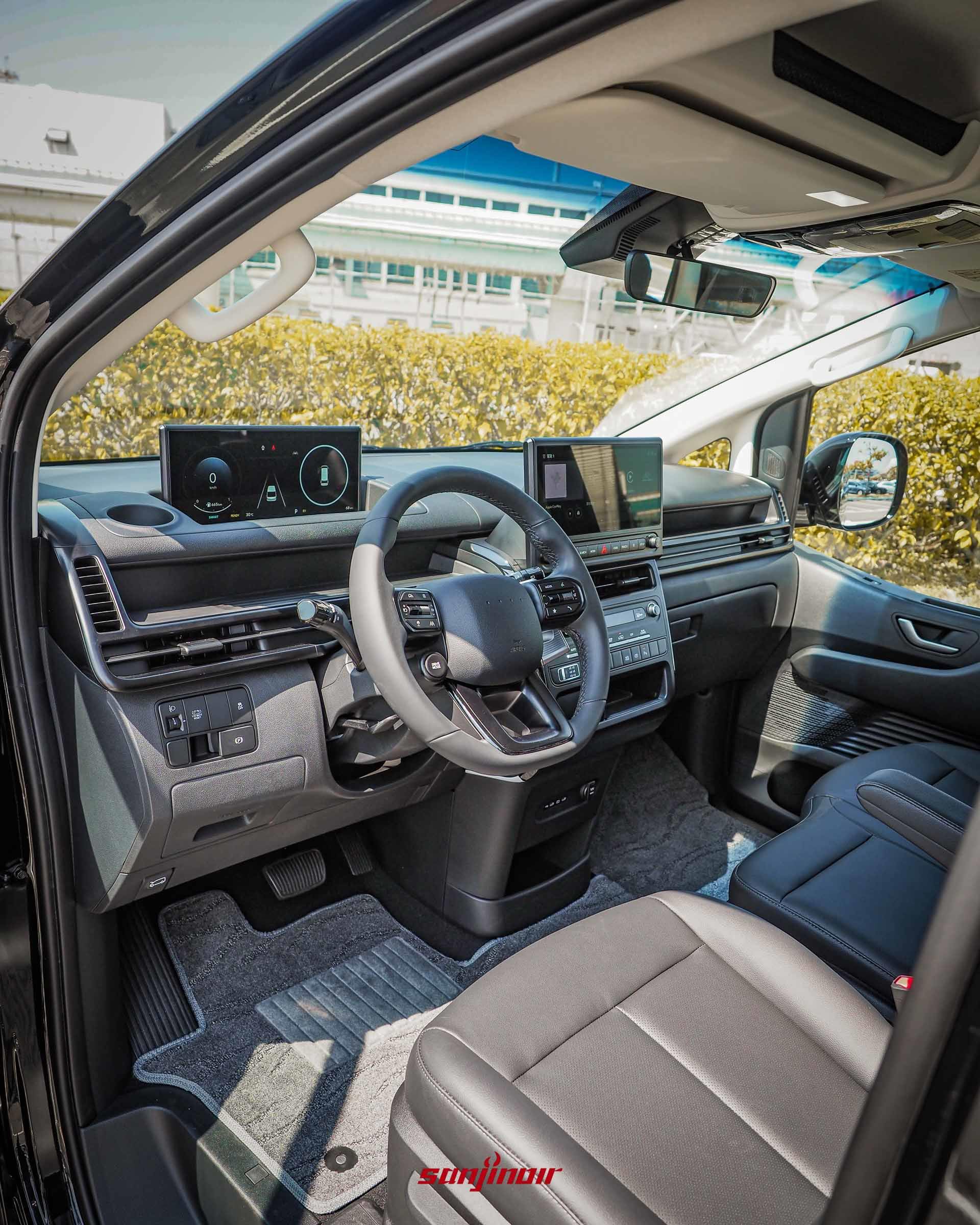 廣角拍攝 Hyundai Staria 駕駛座艙,展示懸浮式數位儀表、中央觸控螢幕、全新方向盤與方向機柱排檔設計。