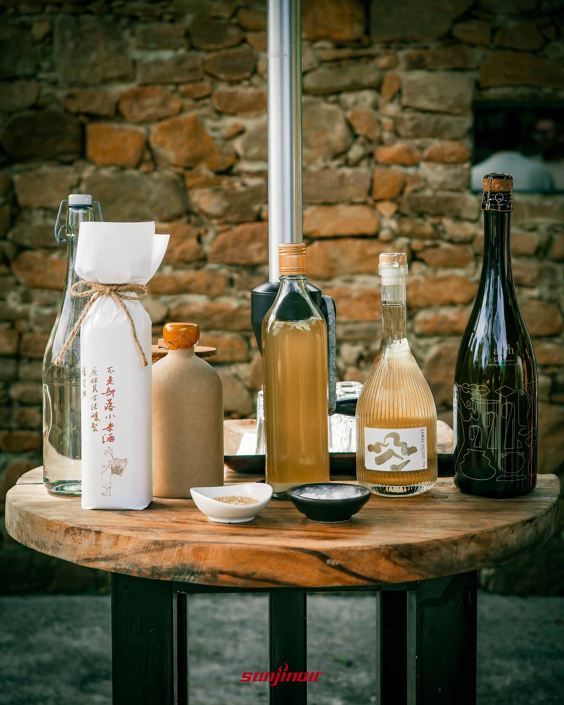 木桌上擺放著多款不同包裝小米酒、清酒與氣泡酒。