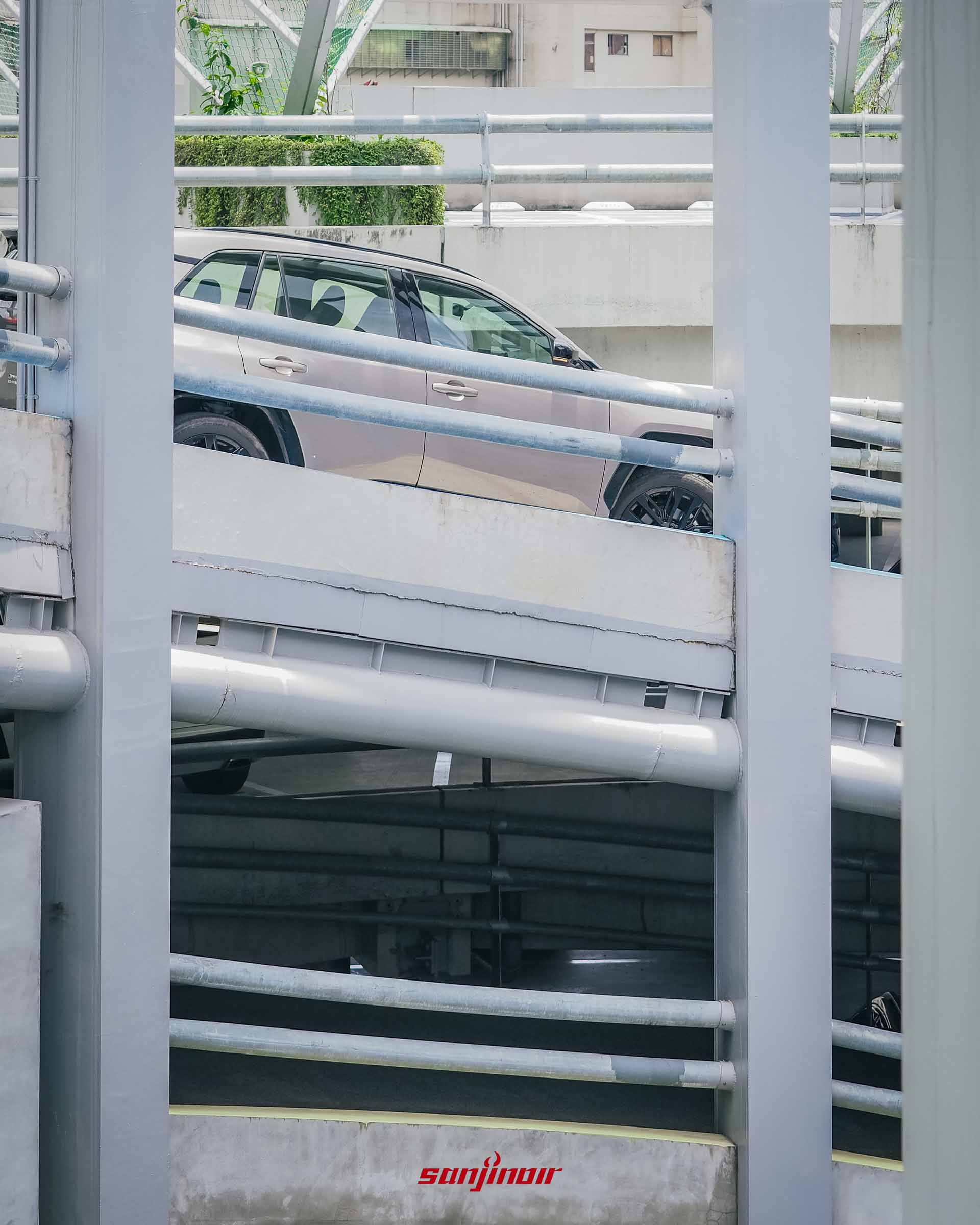 透過停車場水泥樑柱間隙捕捉的RAV4 PHEV車身側面上半部輪廓,展示車窗線條與金屬光澤車漆。